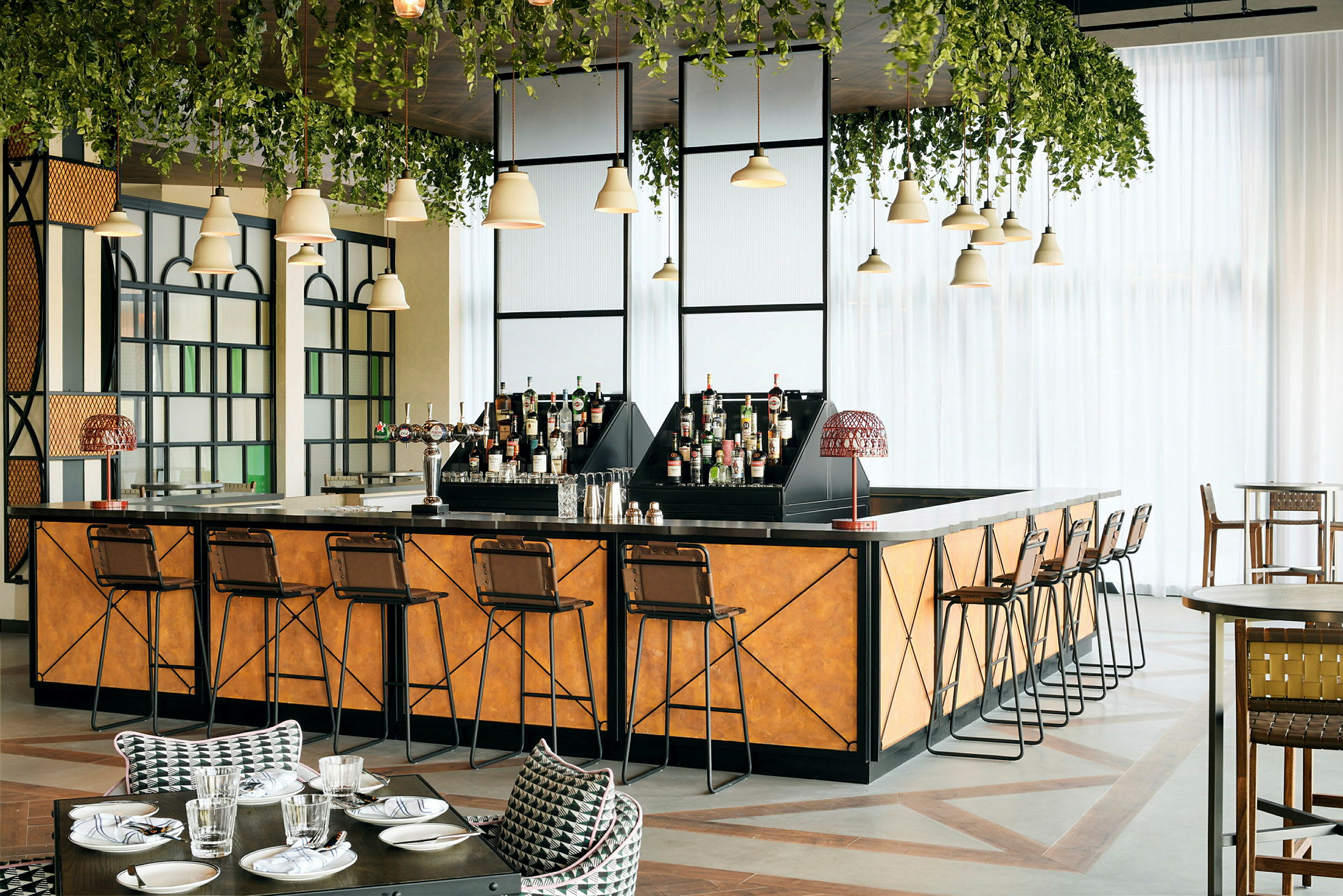 En elegant bar med barstolar, flaskor och gröna hängande växter. (AI-genererad text)