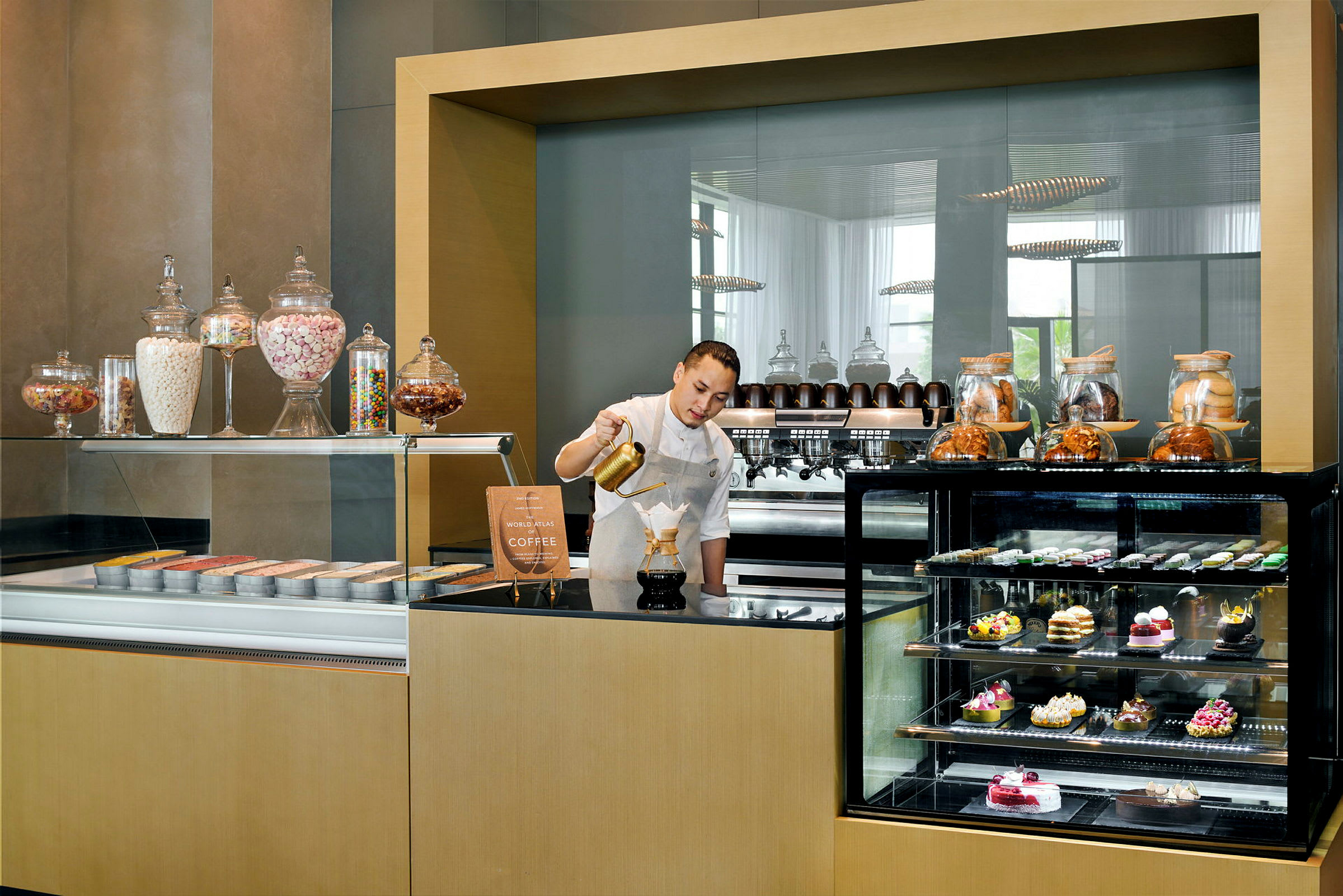 En coffeestation med glasskåp fyllda med bakverk och ingredienser. (AI-genererad text)