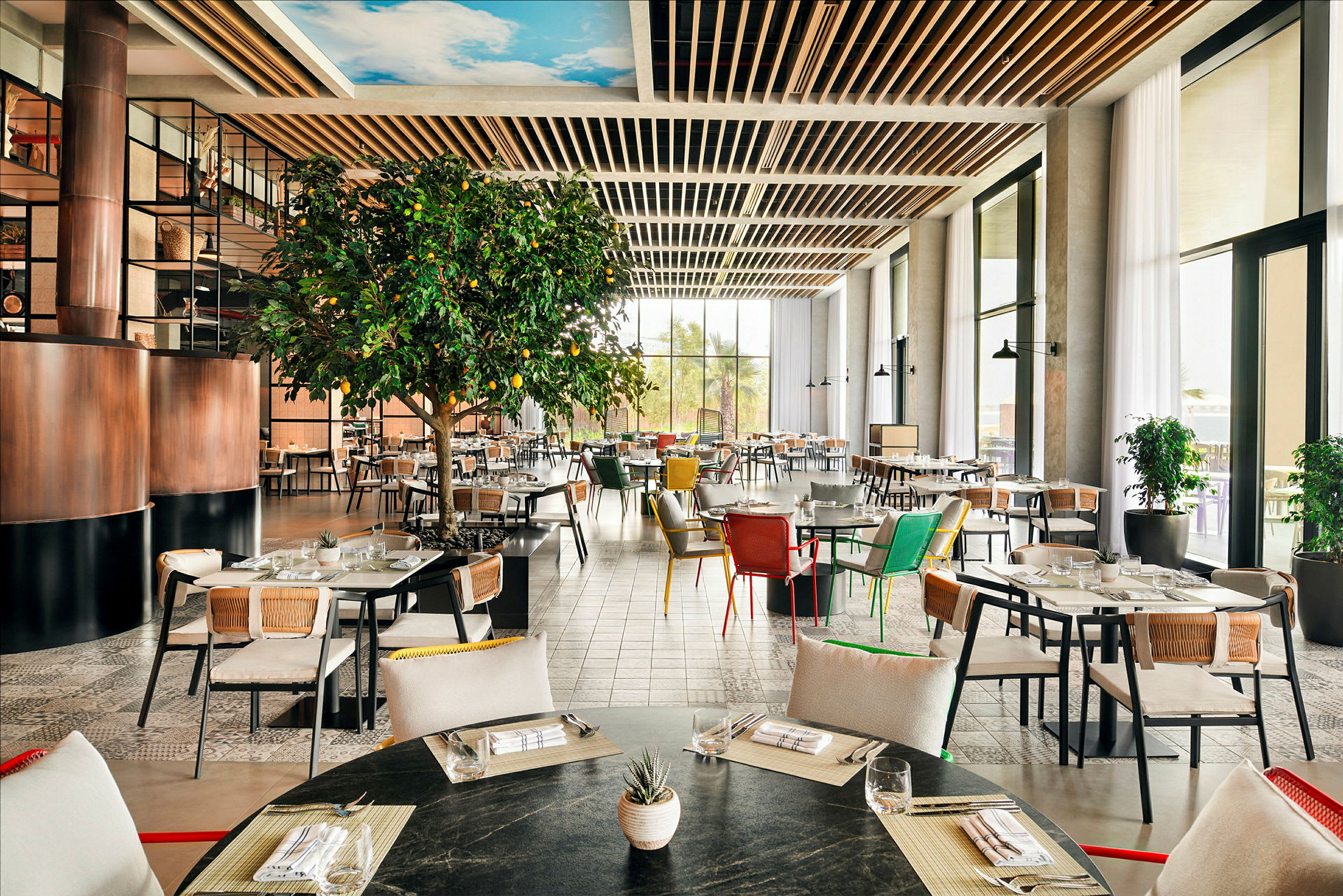 En ljus och rymlig restaurang med moderna möbler och en stor grönskande citronträd. (AI-genererad text)