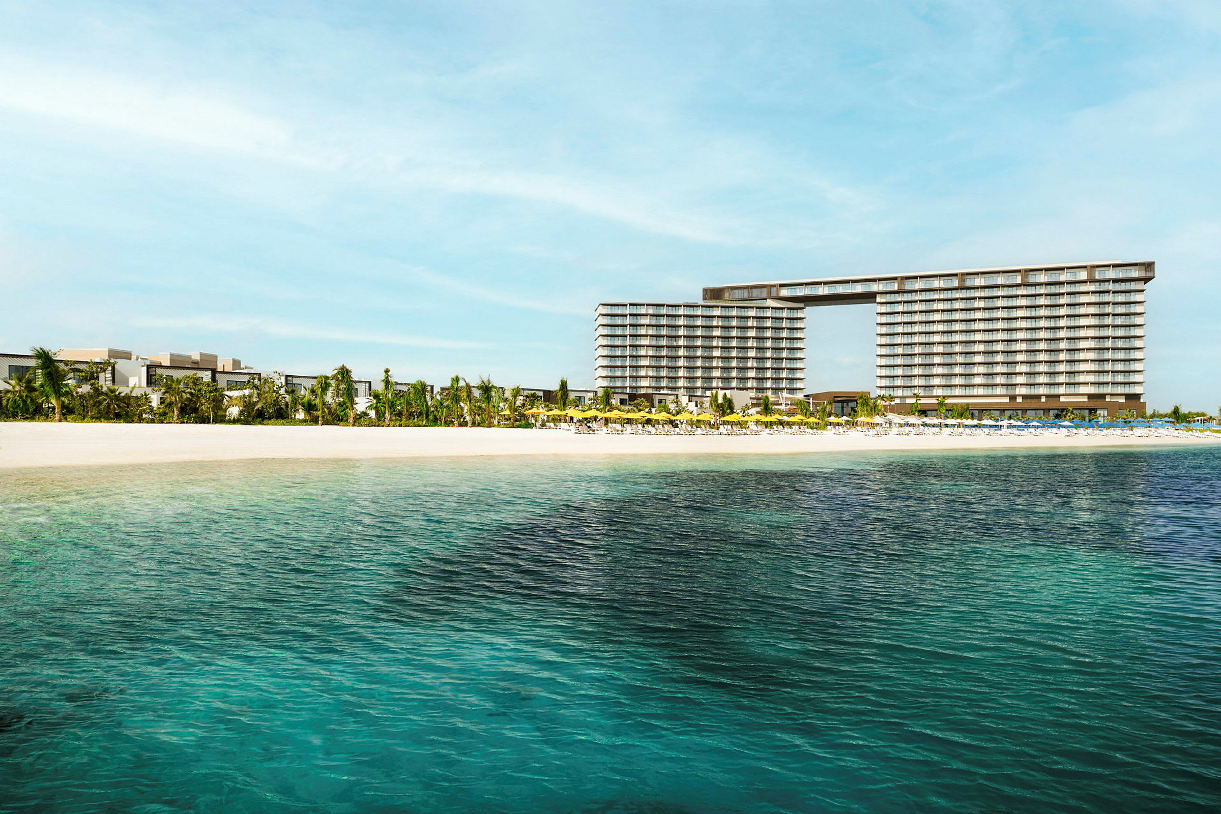 Vy över ett hotell nära en sandstrand med klart vatten. (AI-genererad text)