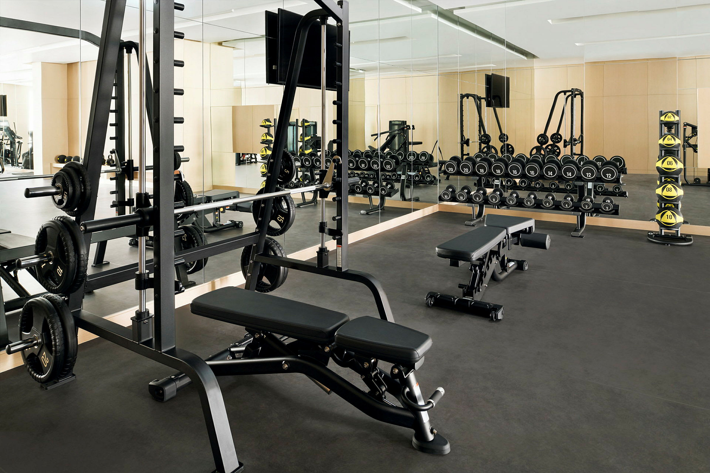 Ett gym med styrketräningsutrustning som inkluderar bänkar, hantlar och vikter. (AI-genererad text)