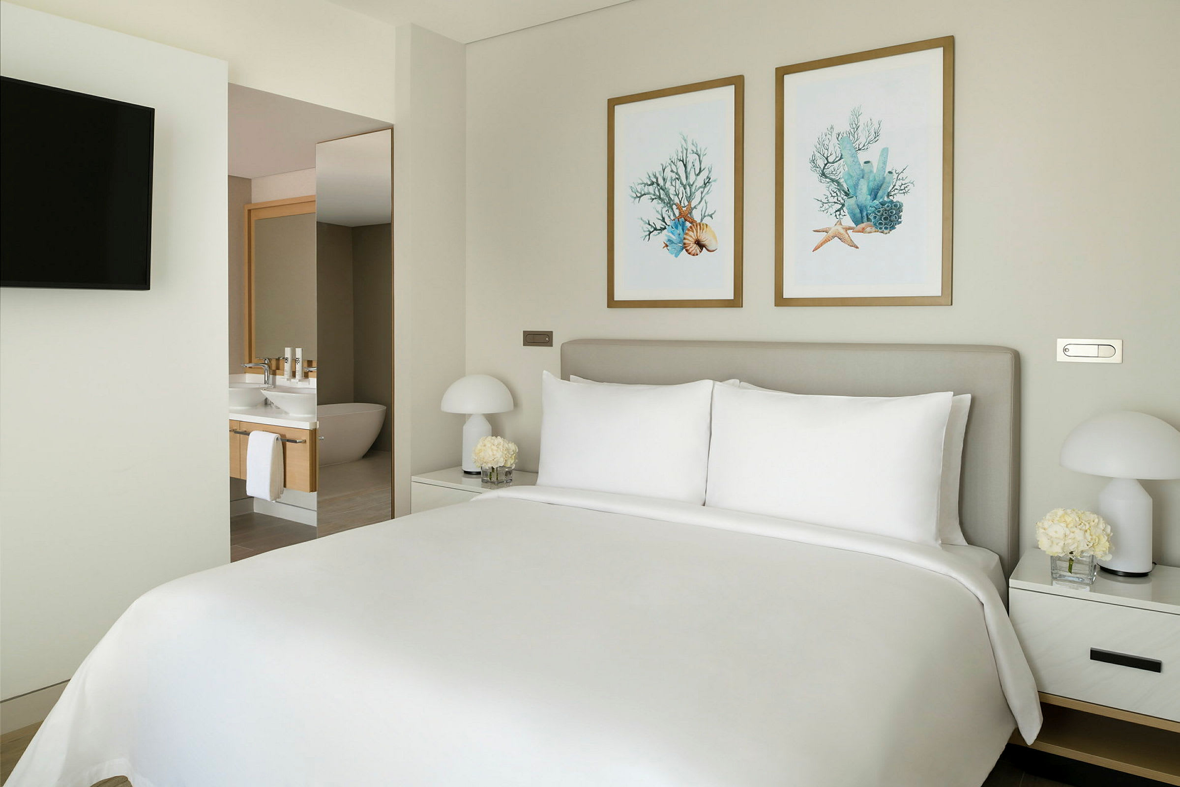 Ett hotellrum med en stor säng, lampor på sängborden och tavlor på väggen. (AI-genererad text)