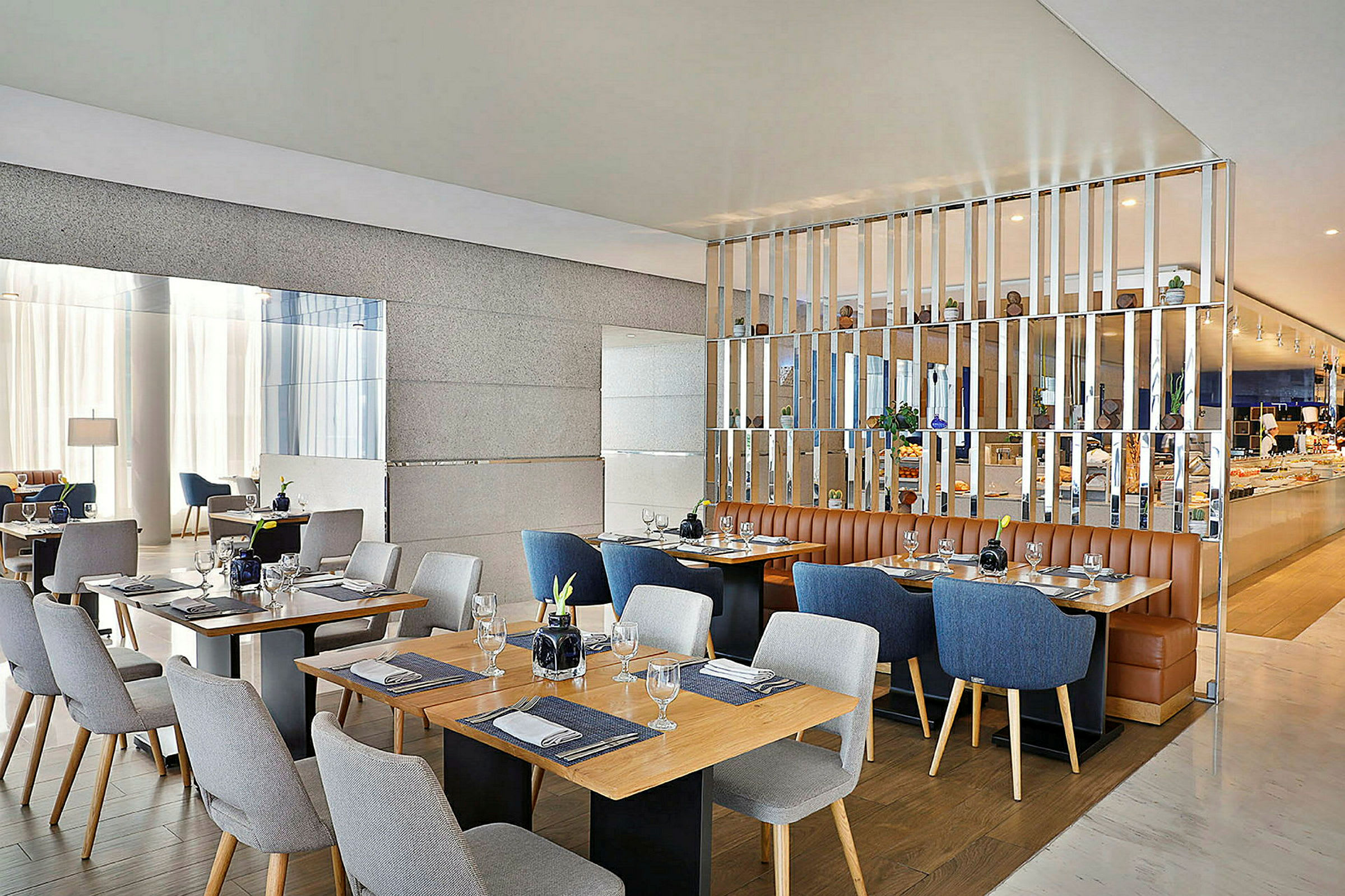 Bild av en modern restaurang med flera dukade bord och stolar i olika färger. Varm och stilren interiör. (AI-genererad text)
