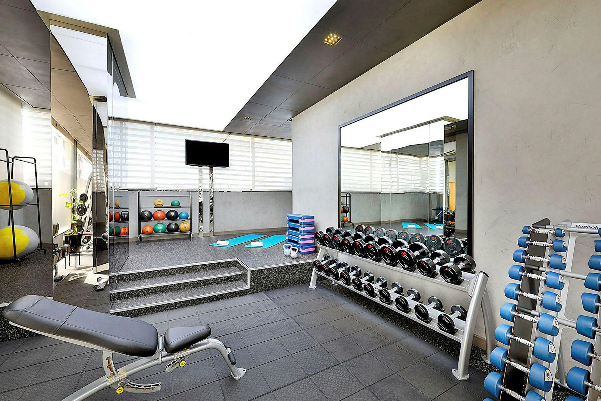Ett modernt gym med träningsbänkar, hantlar och träningsmattor. (AI-genererad text)