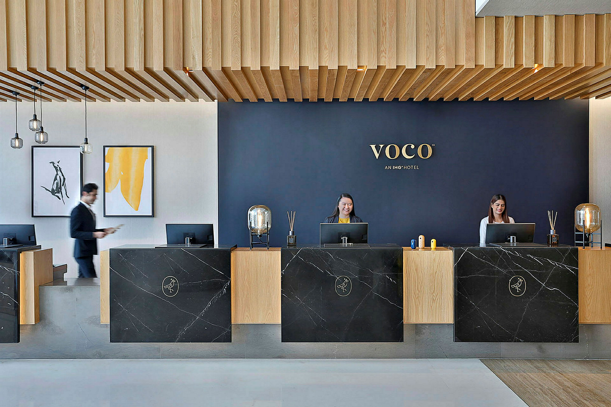 Receptionen på ett hotell med modern design, mörka marmorbänkar och trätak. (AI-genererad text)