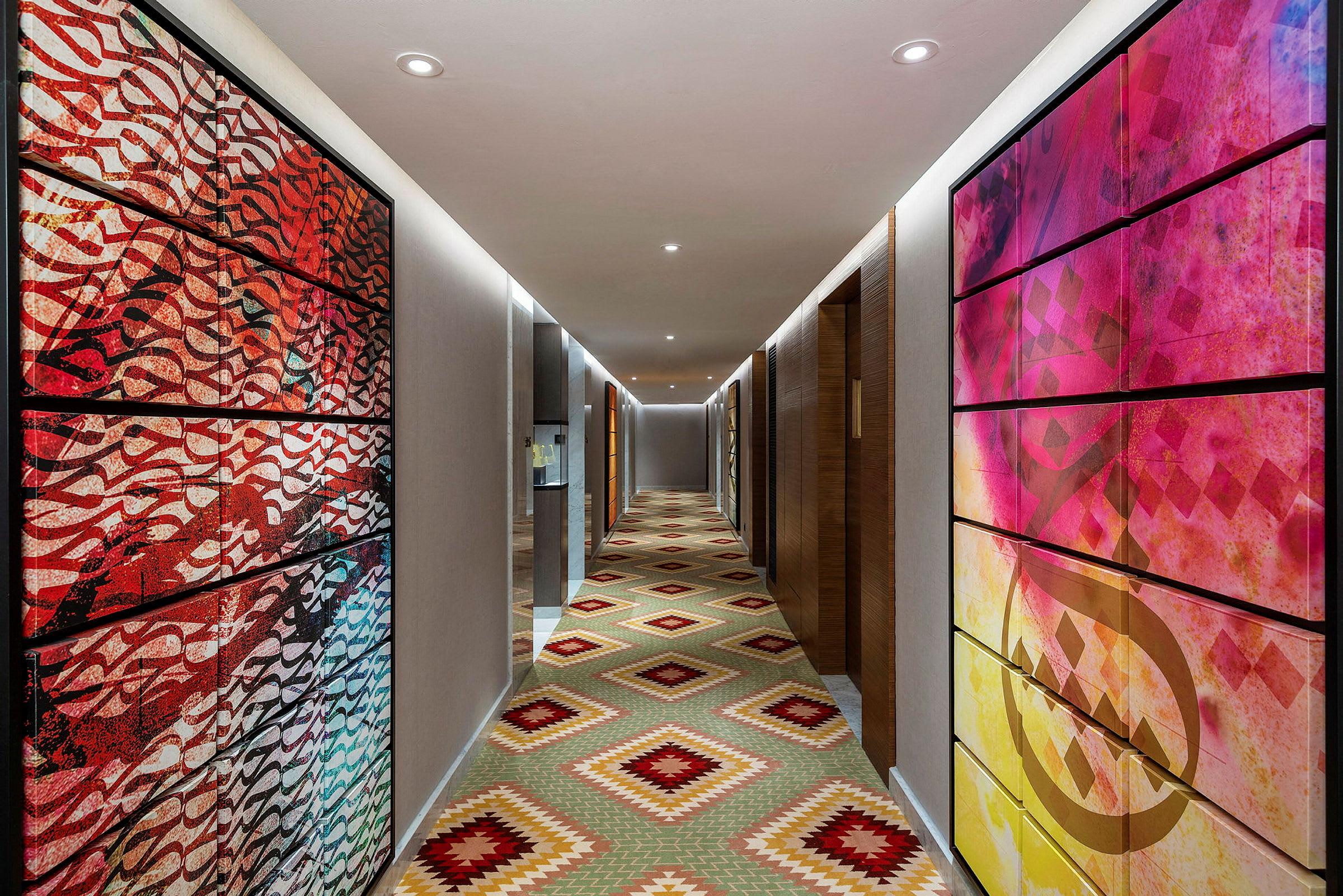 Hotellkorridor med färgglada konstverk på väggarna och ett geometriskt mönstrat golv. (AI-genererad text)