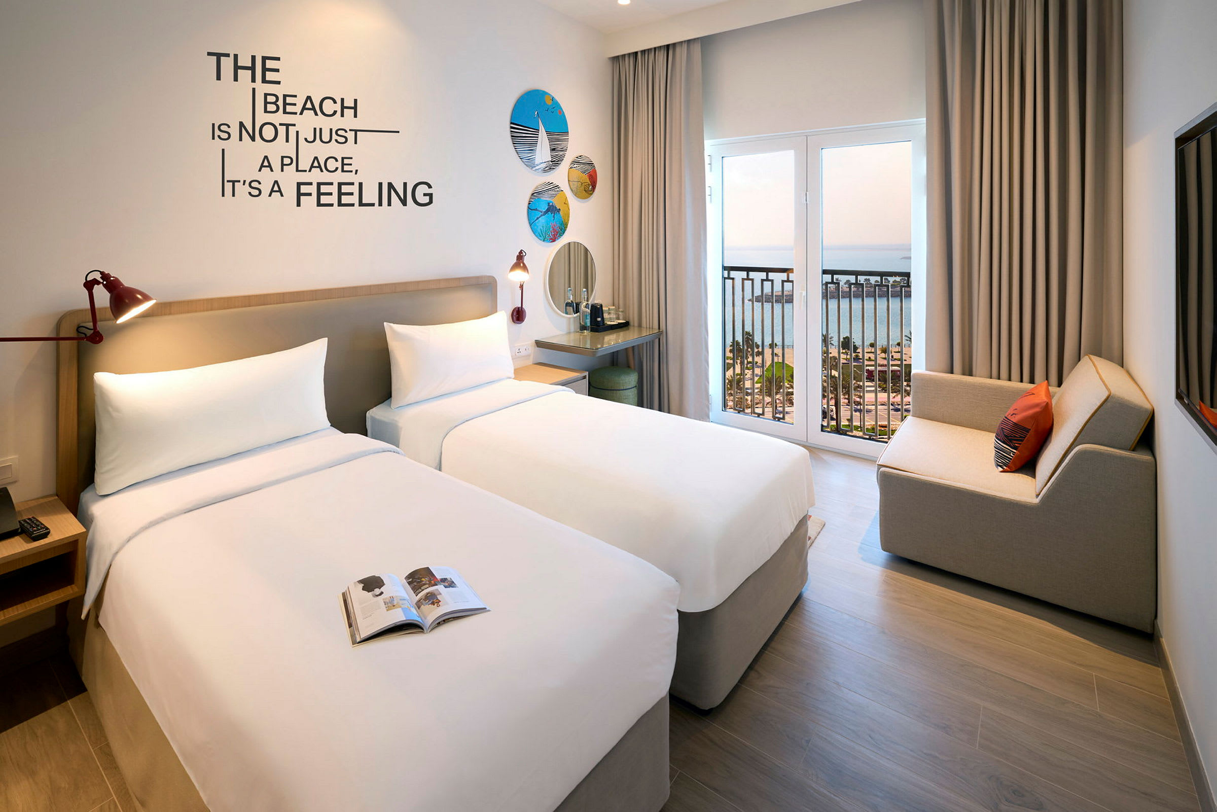 Hotellrum med två enkelsängar, dekorerade med väggprydnader och motiven över strand och hav. (AI-genererad text)