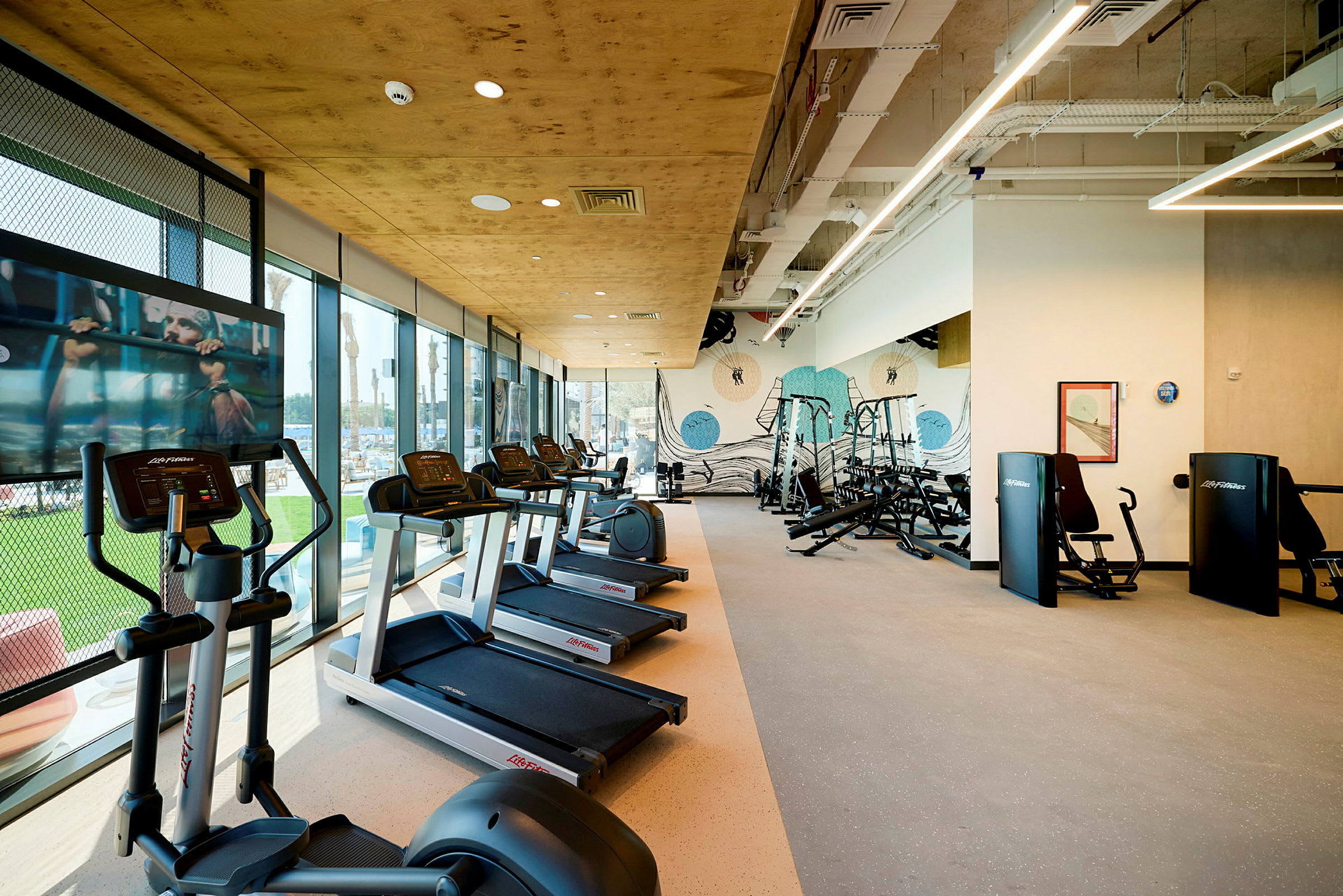Bild av ett gym med löpband, träningsmaskiner och stora fönster. (AI-genererad text)