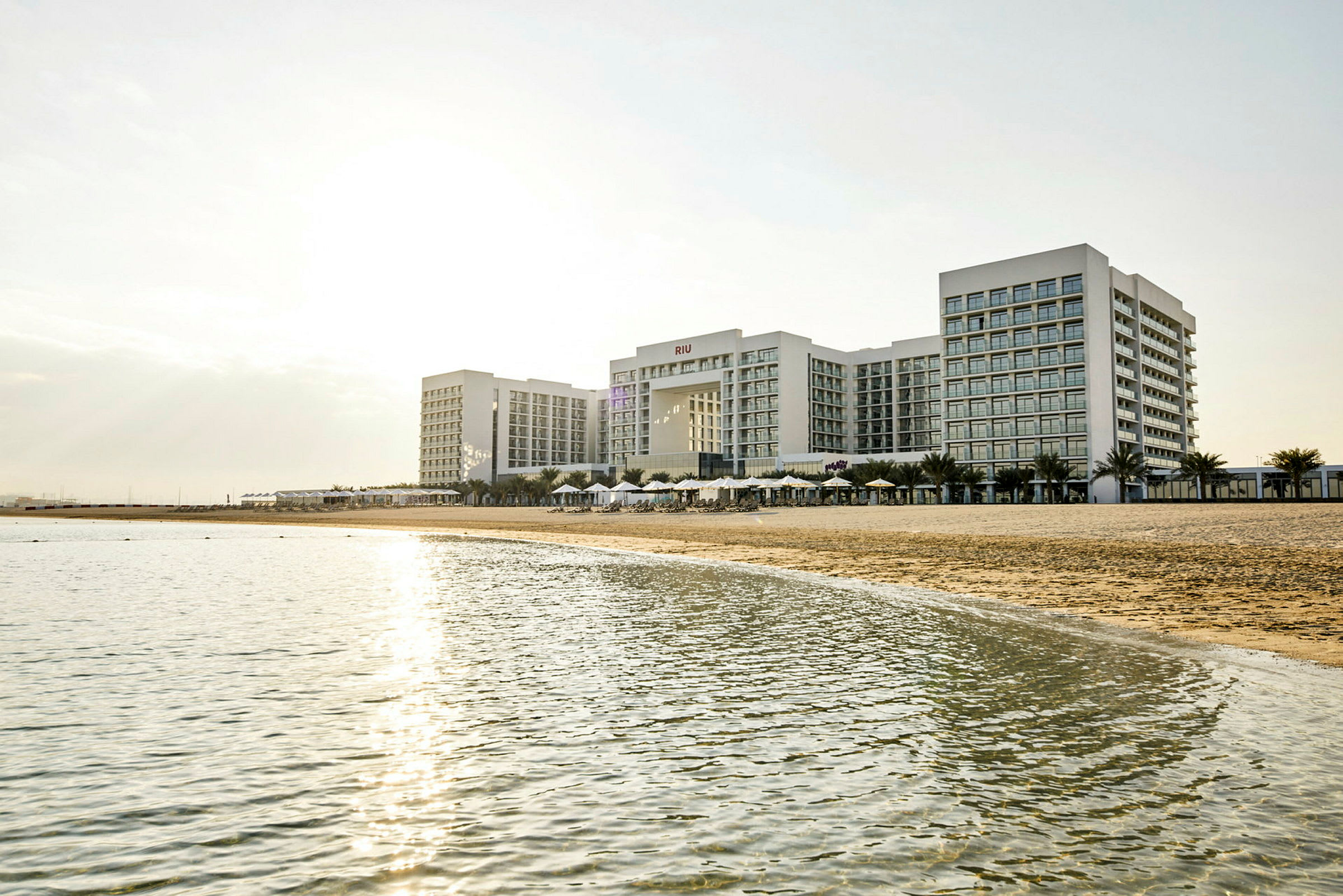 Ett stort hotellkomplex vid en strand med hav i förgrunden. (AI-genererad text)