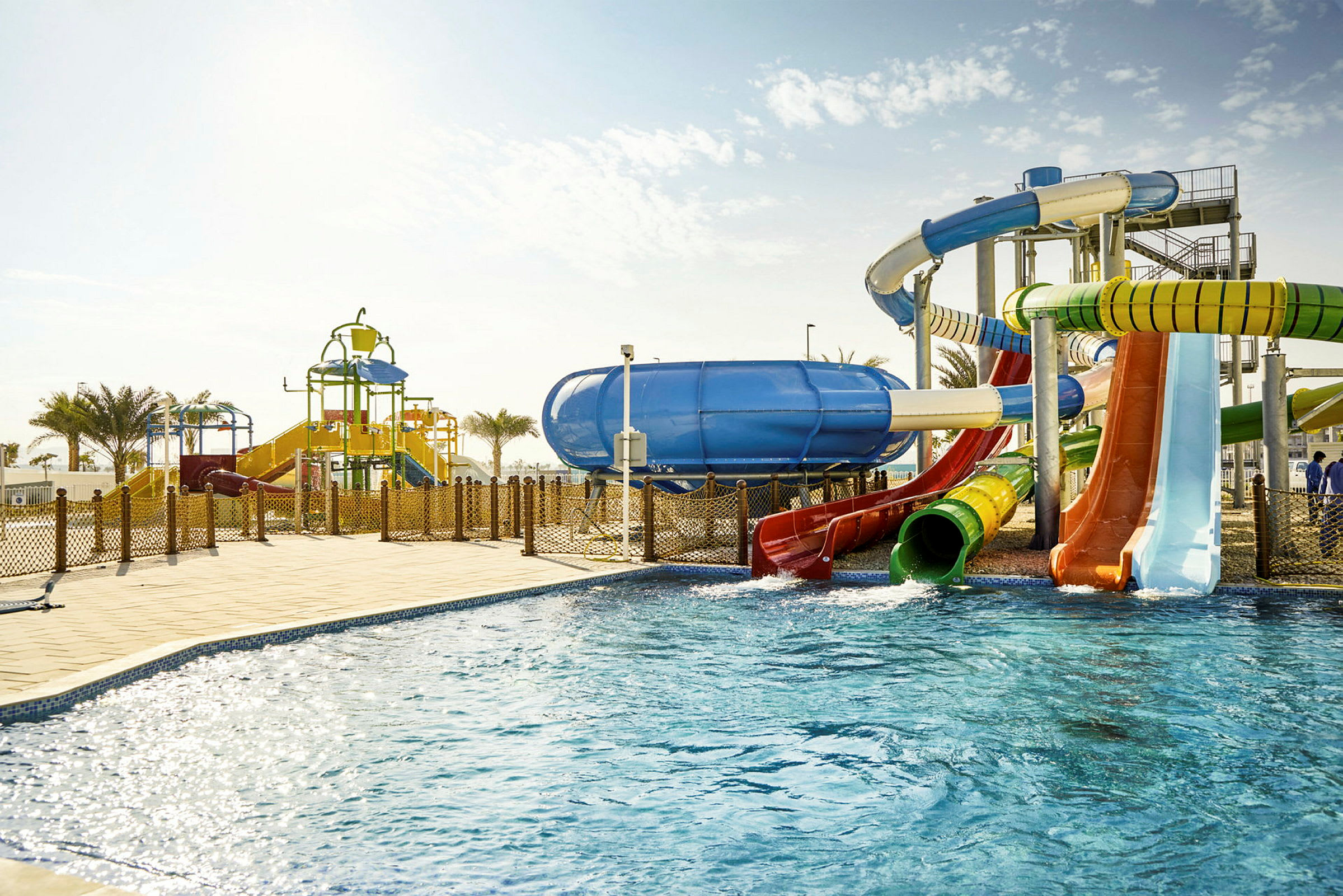 En utomhusvattenpark med pool och vattenrutschbanor i olika färger. (AI-genererad text)