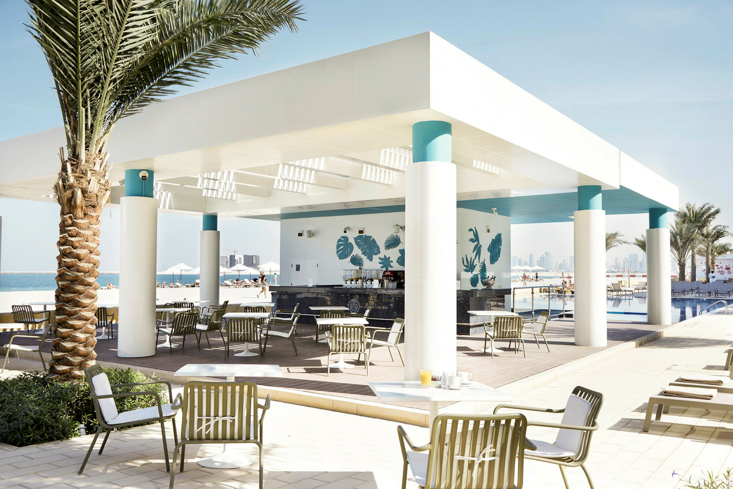 En utomhusrestaurang med tak och pelare, omgiven av solstolar och palmer vid poolområdet. (AI-genererad text)