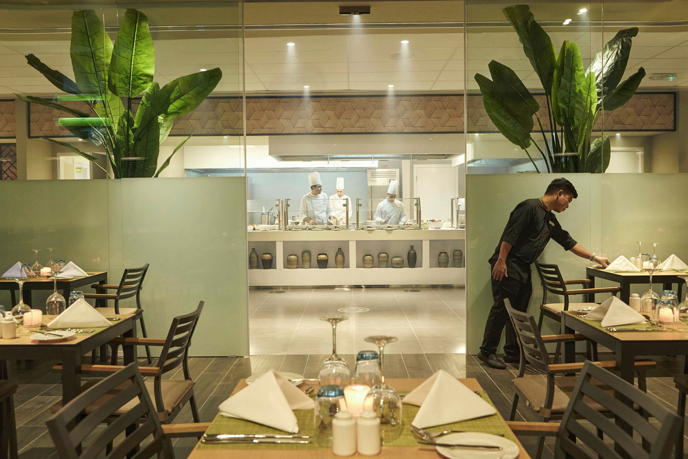 En restaurang med prydligt dukade bord och öppet kök i bakgrunden. (AI-genererad text)