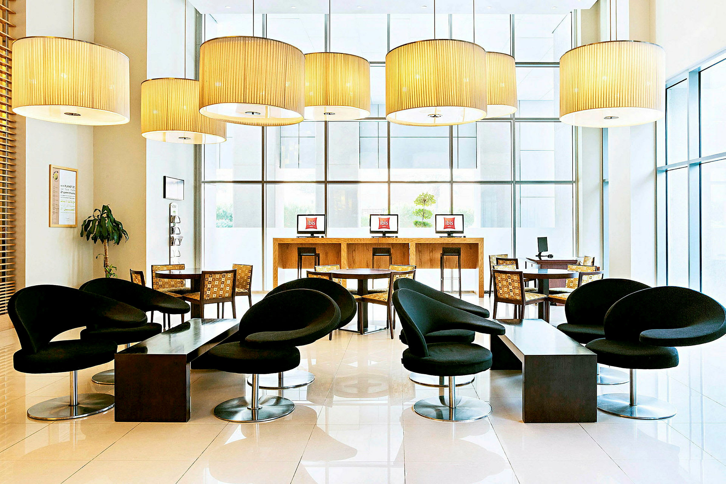 Ett modernt möblerat hotellobbyn med svarta stolar, bord och datorstationer. (AI-genererad text)