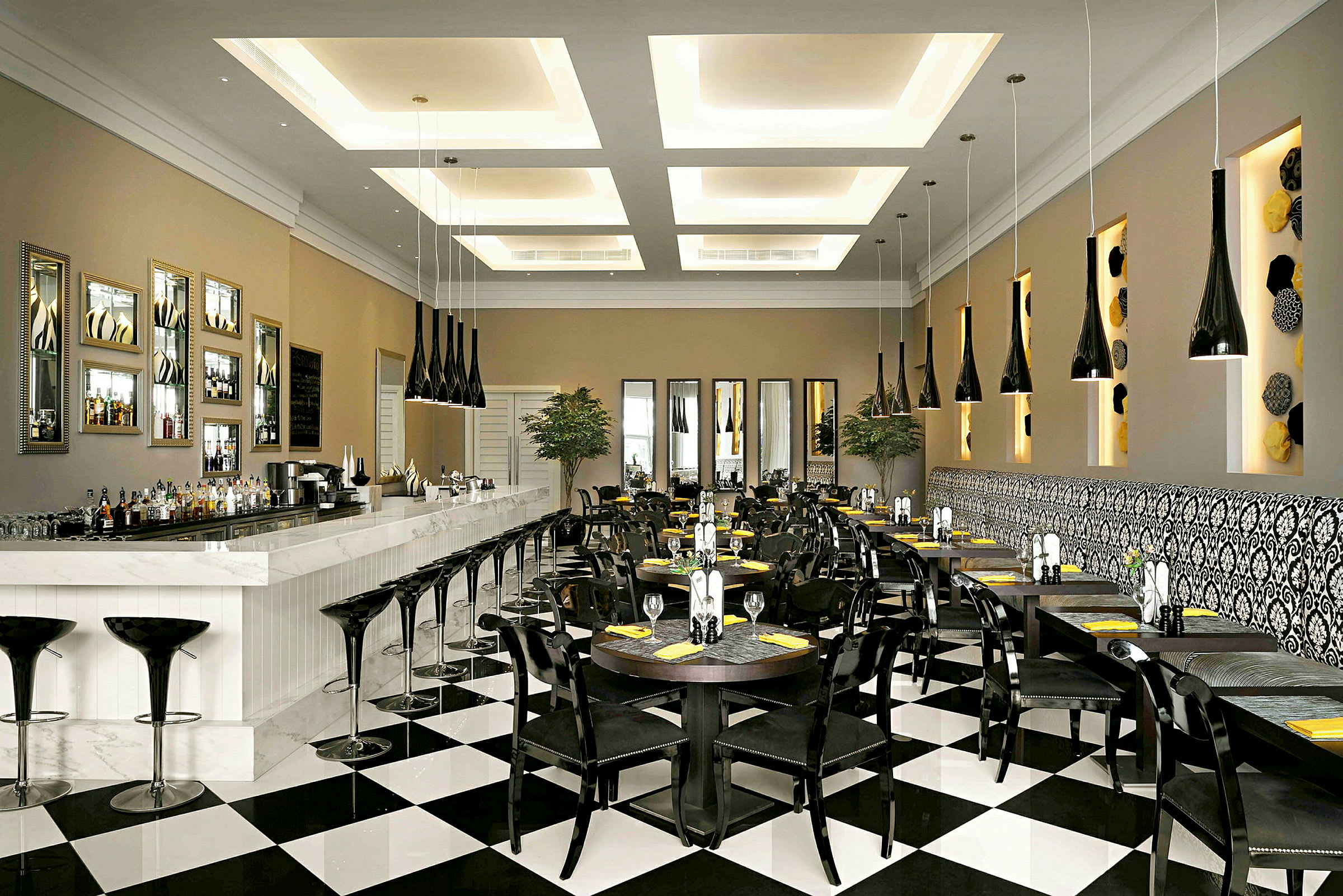 En elegant restaurang eller café med en lång vit bardisk, svarta stolar, bordsuppsättningar och distinkt modern inredning. (AI-genererad text)