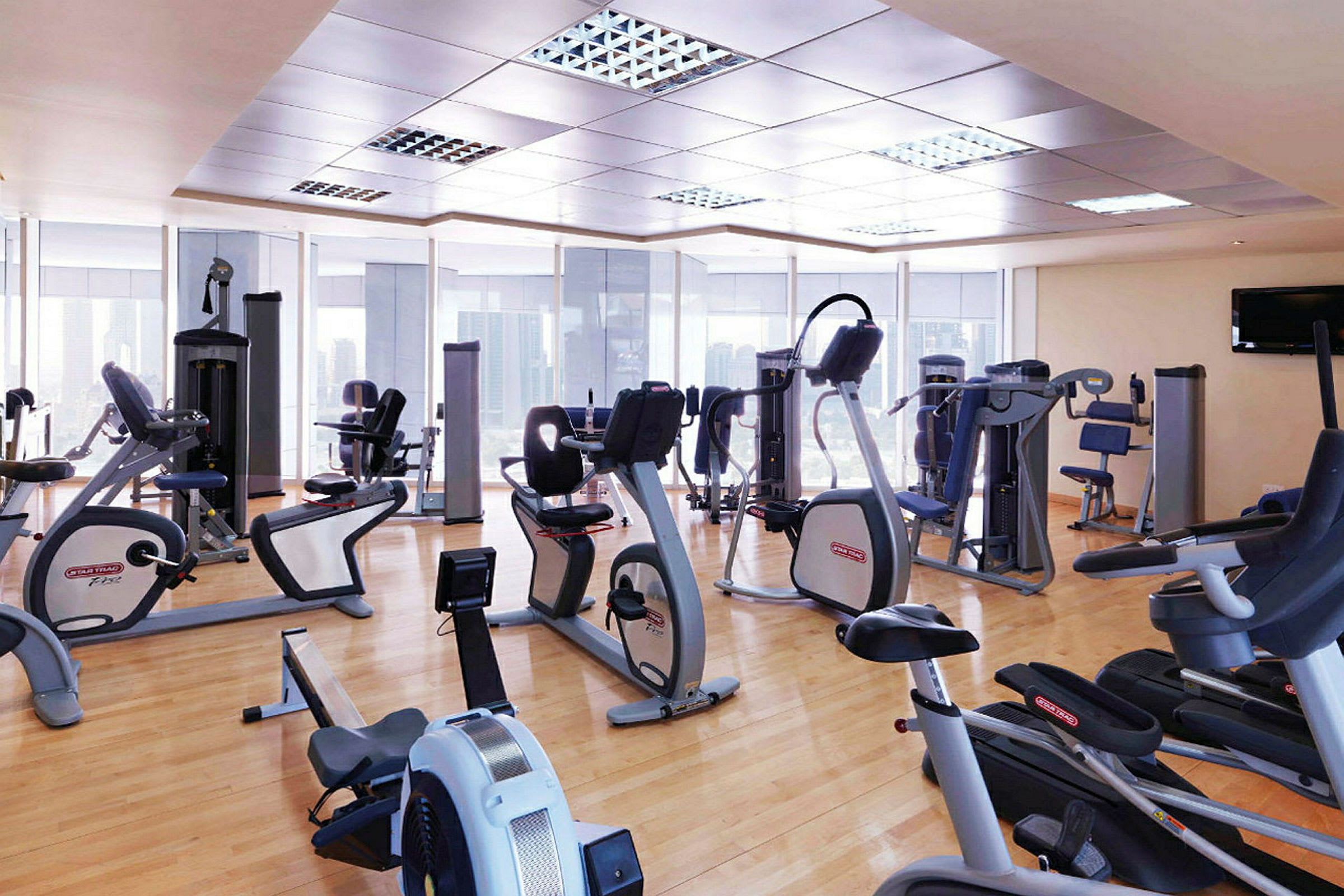 Gym med olika träningsmaskiner och stort glasfönster. (AI-genererad text)