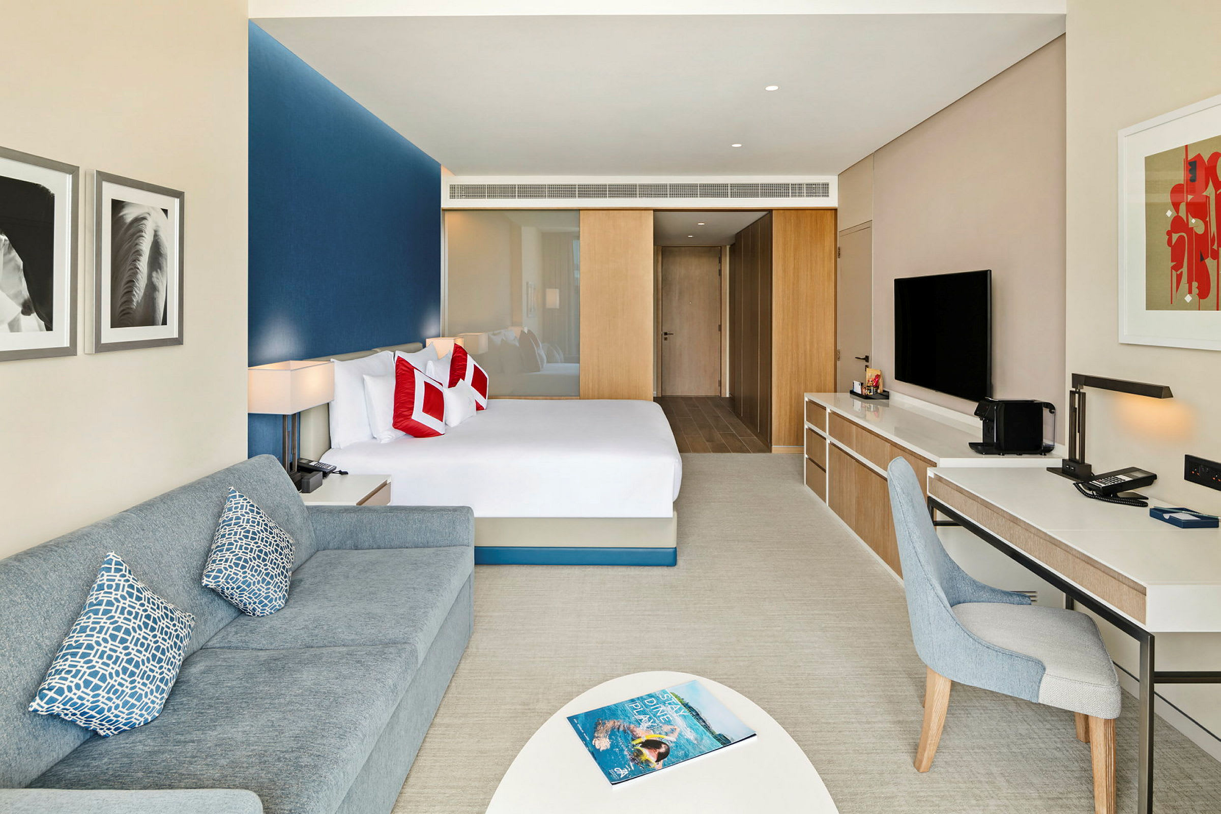 Modernt hotellrum med säng, soffa och arbetsbord. (AI-genererad text)