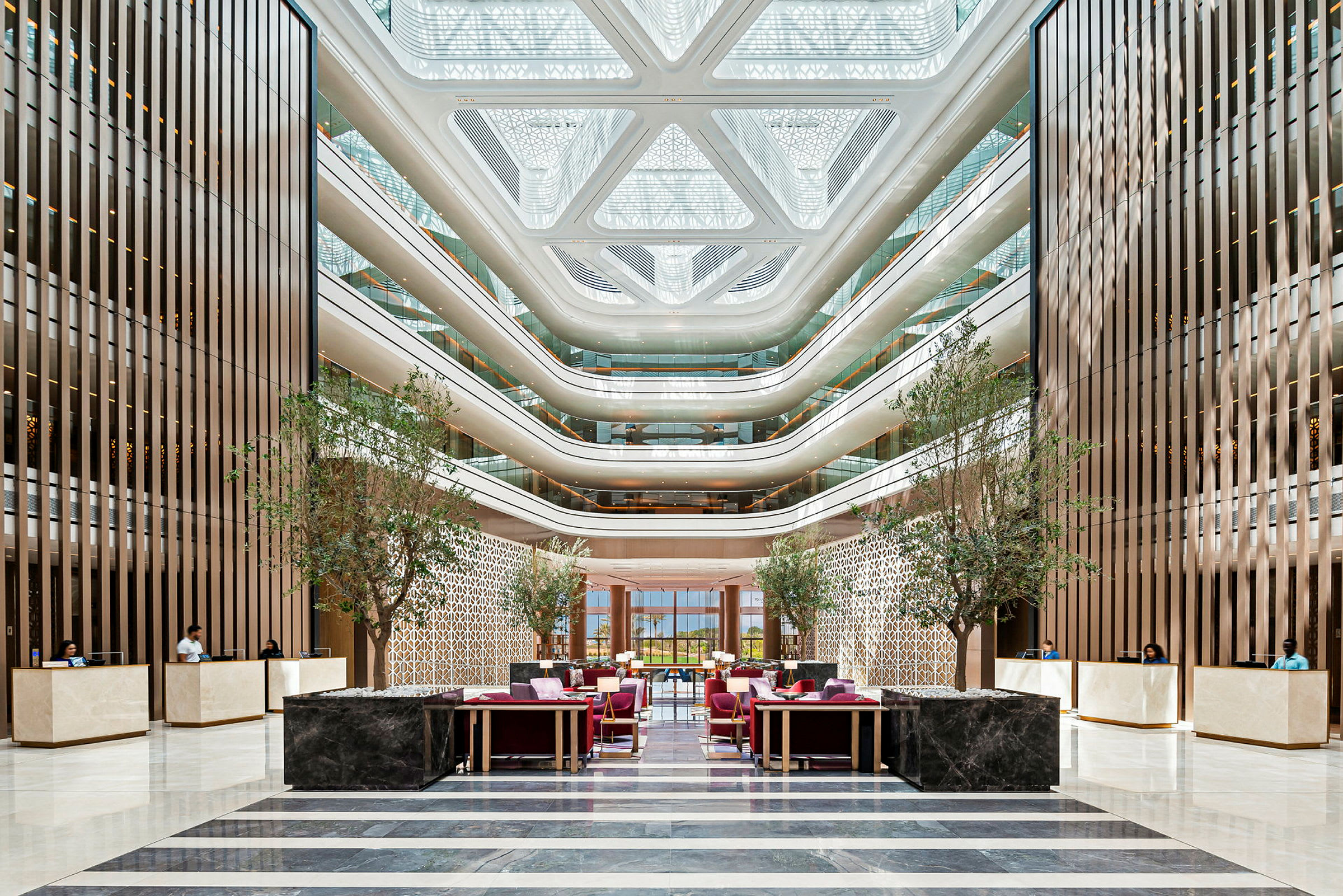 Ett modernt hotellatrium med flera våningar, stora fönster, dekorativa träpaneler och receptioner. (AI-genererad text)