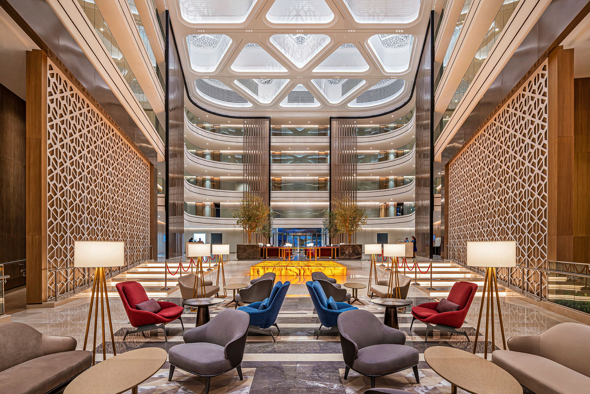 Ett elegant hotellobbyutrymme med moderna sittgrupper, golvlampor och en imponerande takdesign. (AI-genererad text)