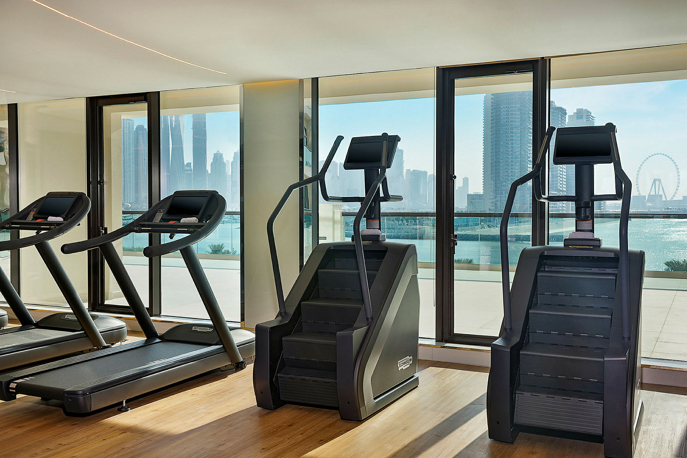 Träningsmaskiner i ett gym med utsikt över en stadssilhuett. (AI-genererad text)