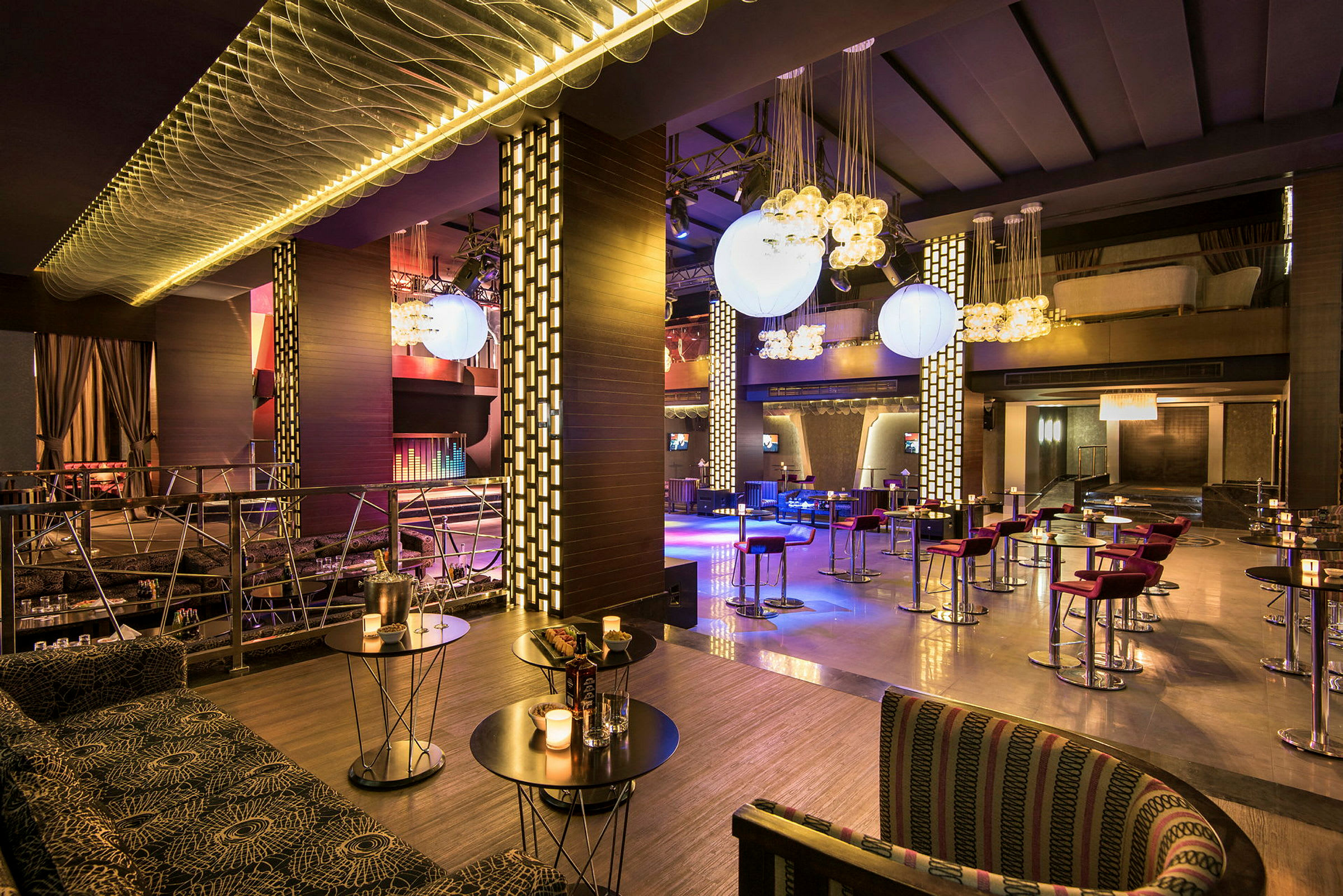 En modern restaurant med bord och stolar, samt dekorativa ljushängningar. (AI-genererad text)