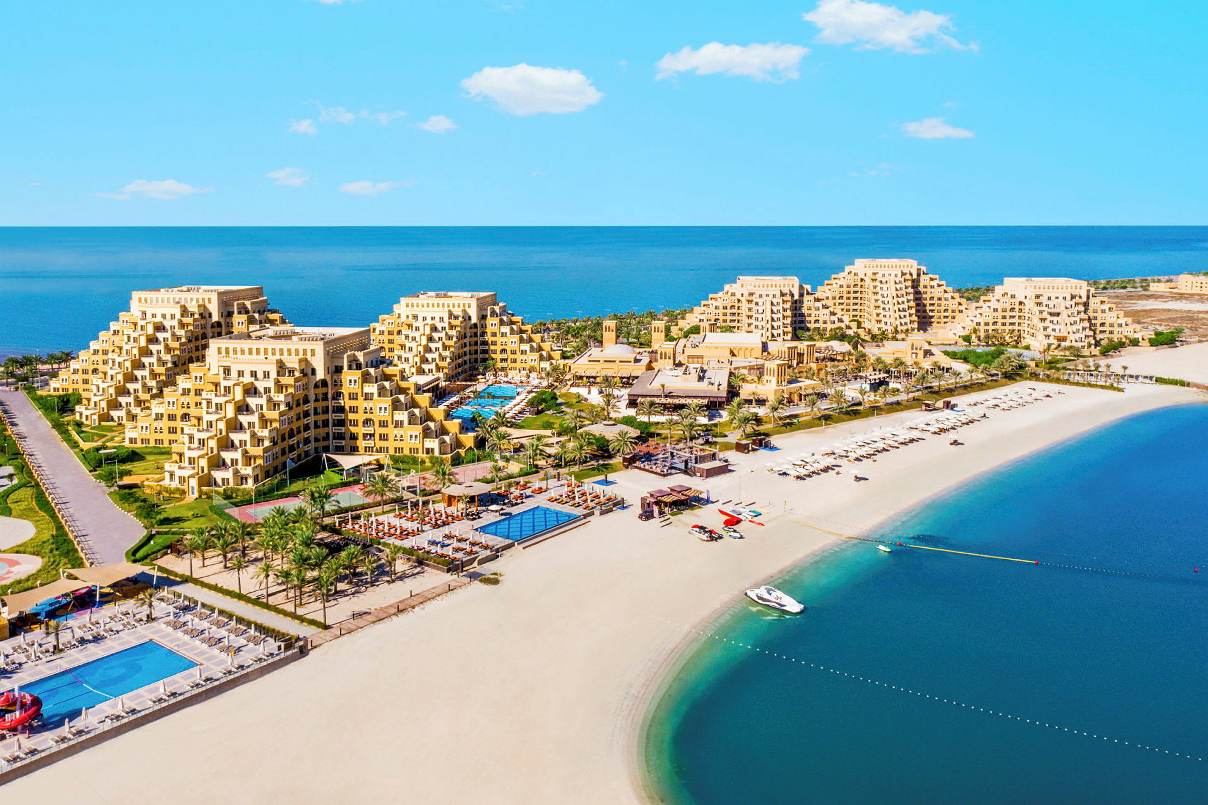 Ett hotellkomplex vid en strand med pooler och palmer. (AI-genererad text)