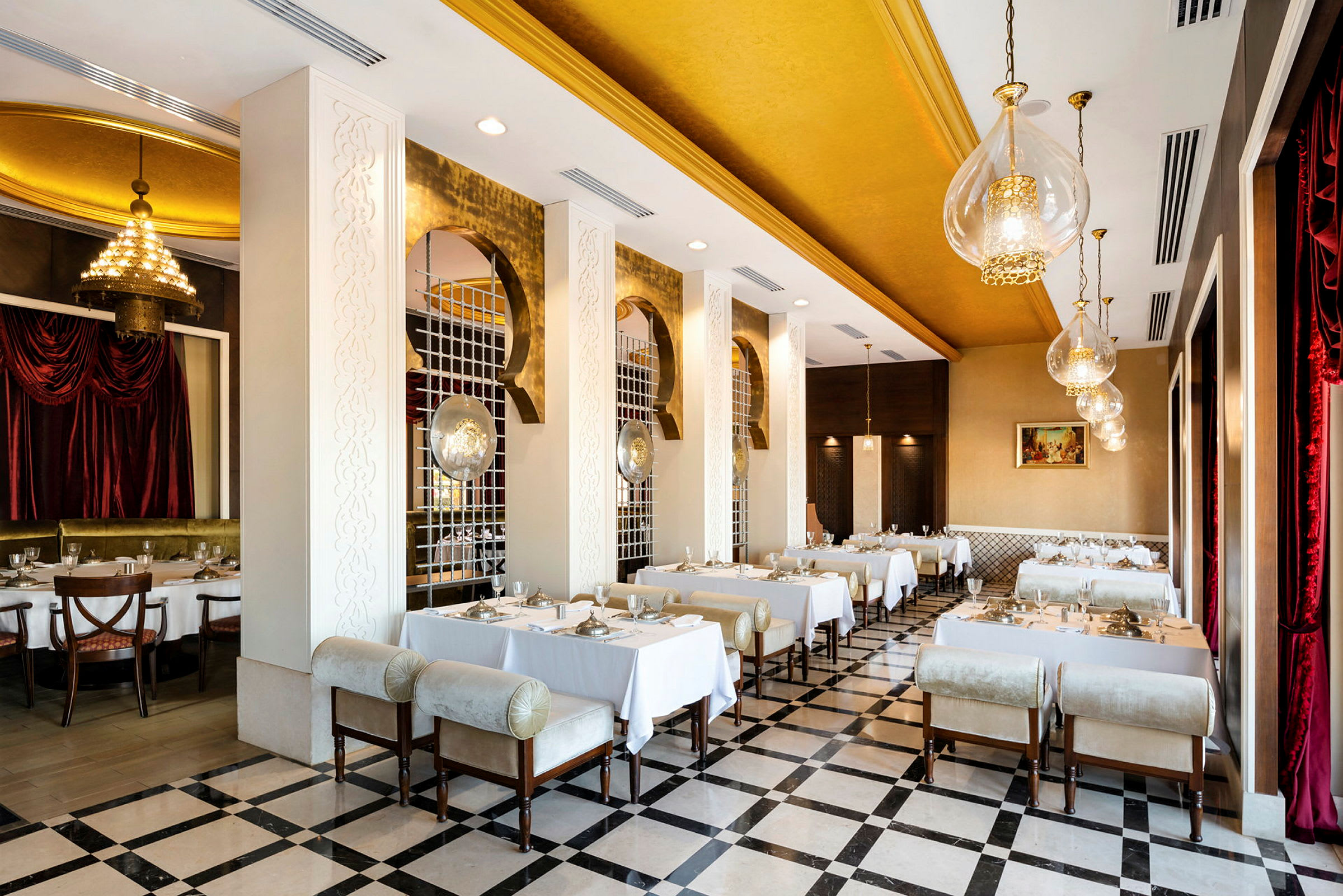 En elegant restaurang med gulddetaljer och vita dukar på borden. (AI-genererad text)