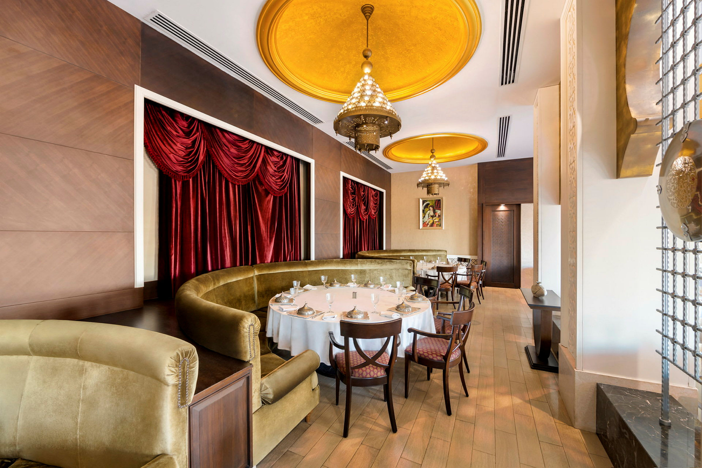 Interiör av en elegant restaurang med guldfärgade takdetaljer och röda gardiner. (AI-genererad text)