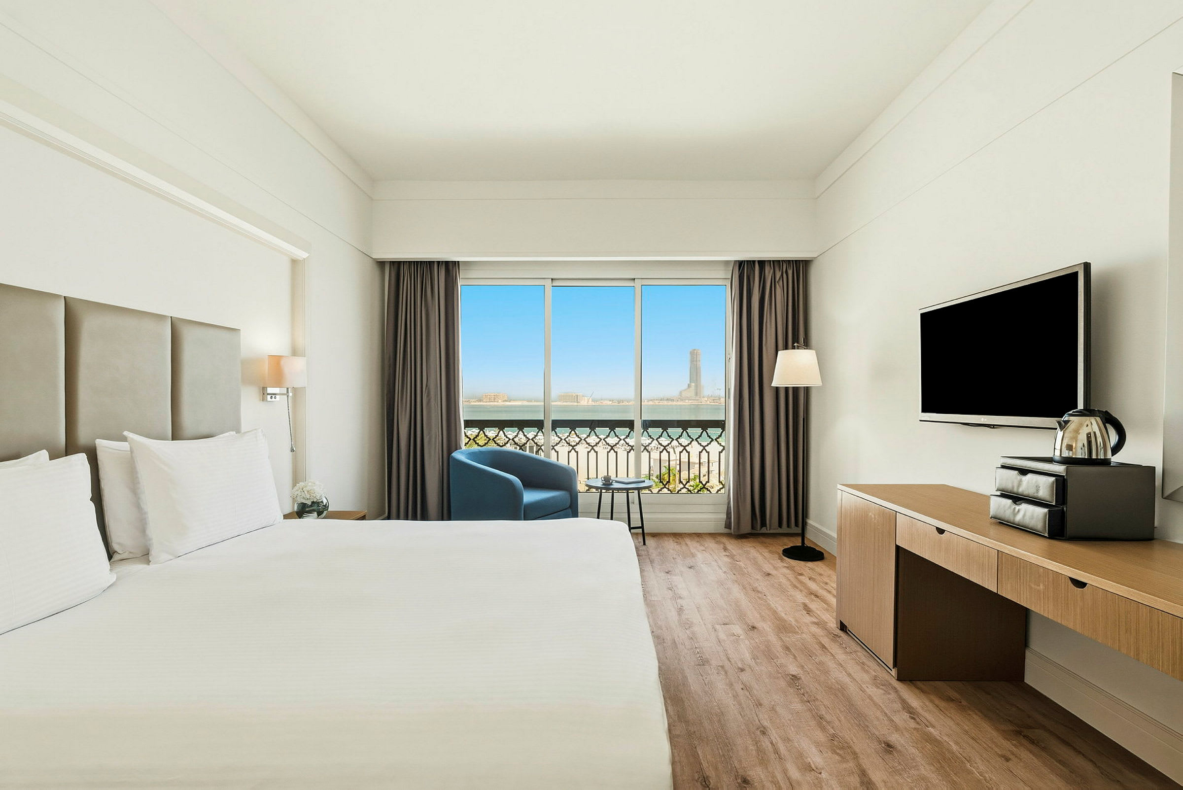 Ett modernt hotellrum med en stor säng, en TV, en fåtölj och ett fönster med utsikt. (AI-genererad text)