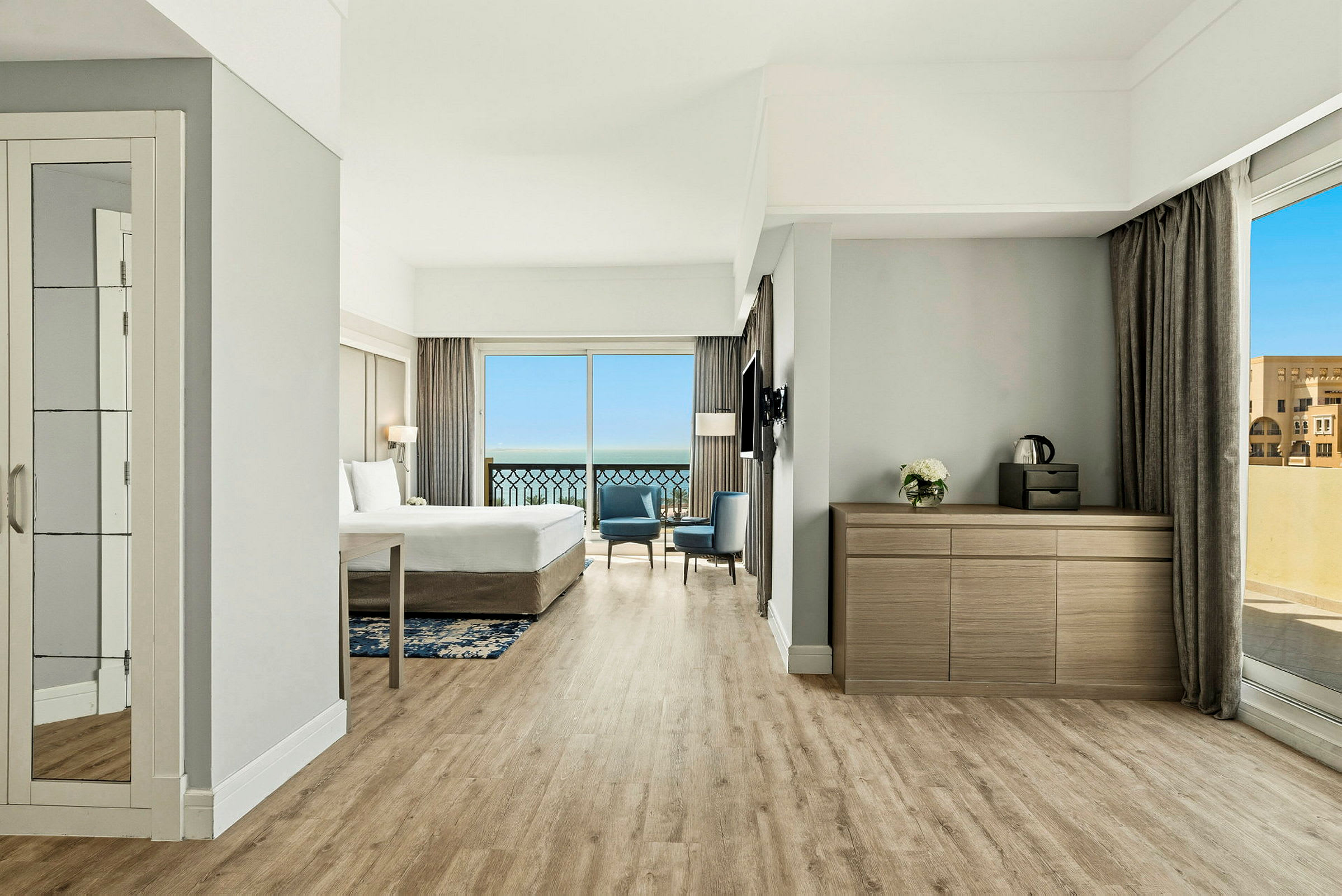 Bild av ett hotellrum med en stor säng, sittmöbler och fönster med utsikt mot havet. (AI-genererad text)