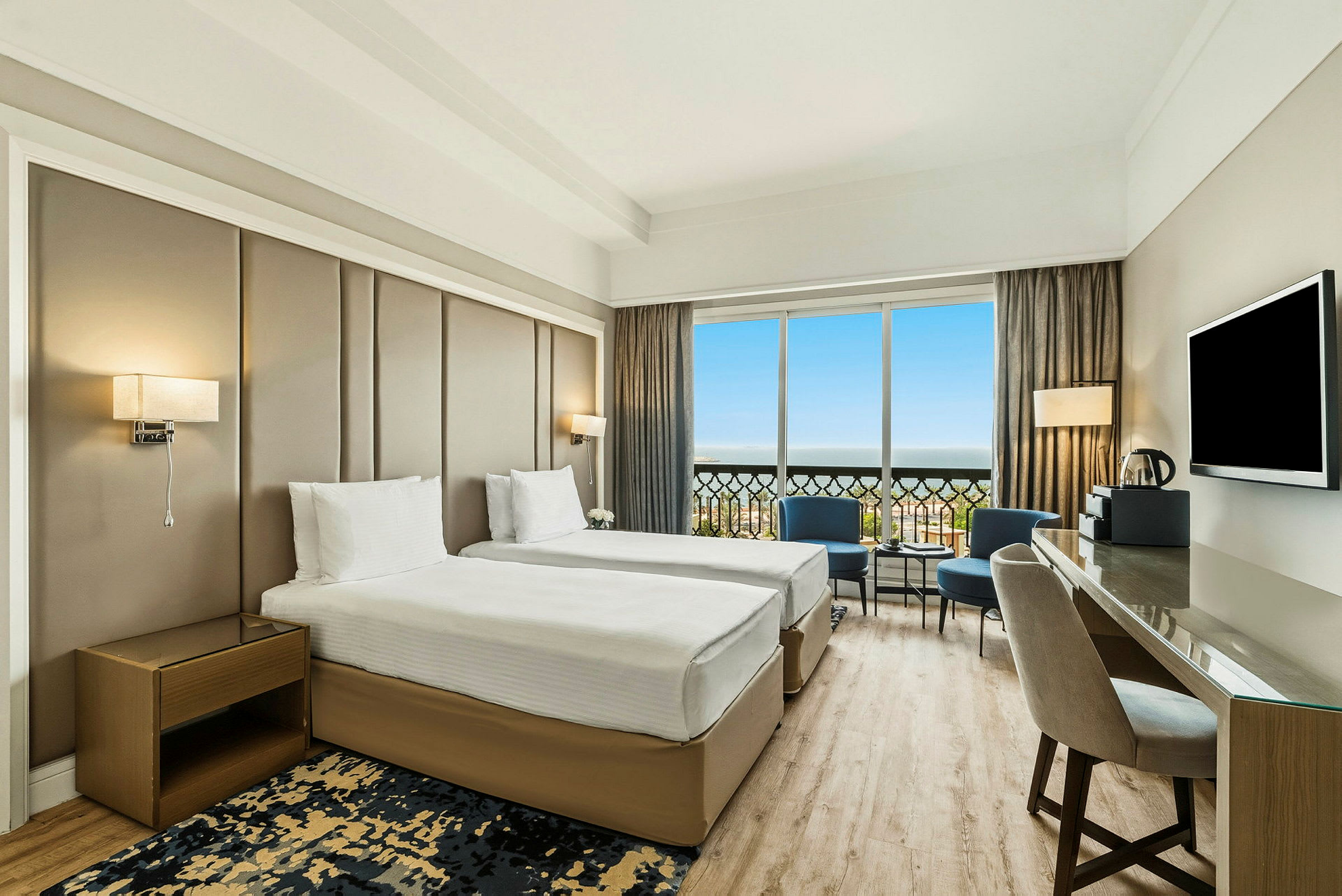 Ett modernt hotellrum med två sängar, en arbetsyta och en stor fönstervy. (AI-genererad text)