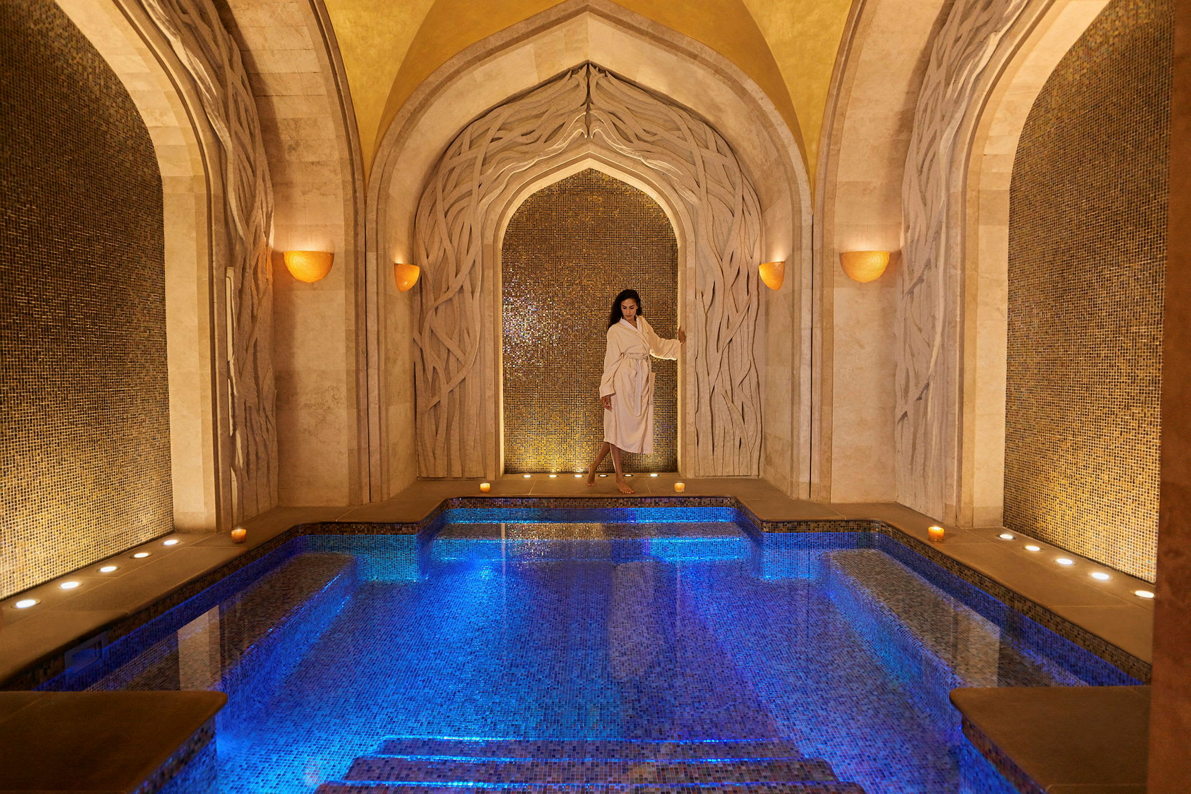Elegant spa-miljö med upplyst mosaikpool och dekorativa valv. (AI-genererad text)