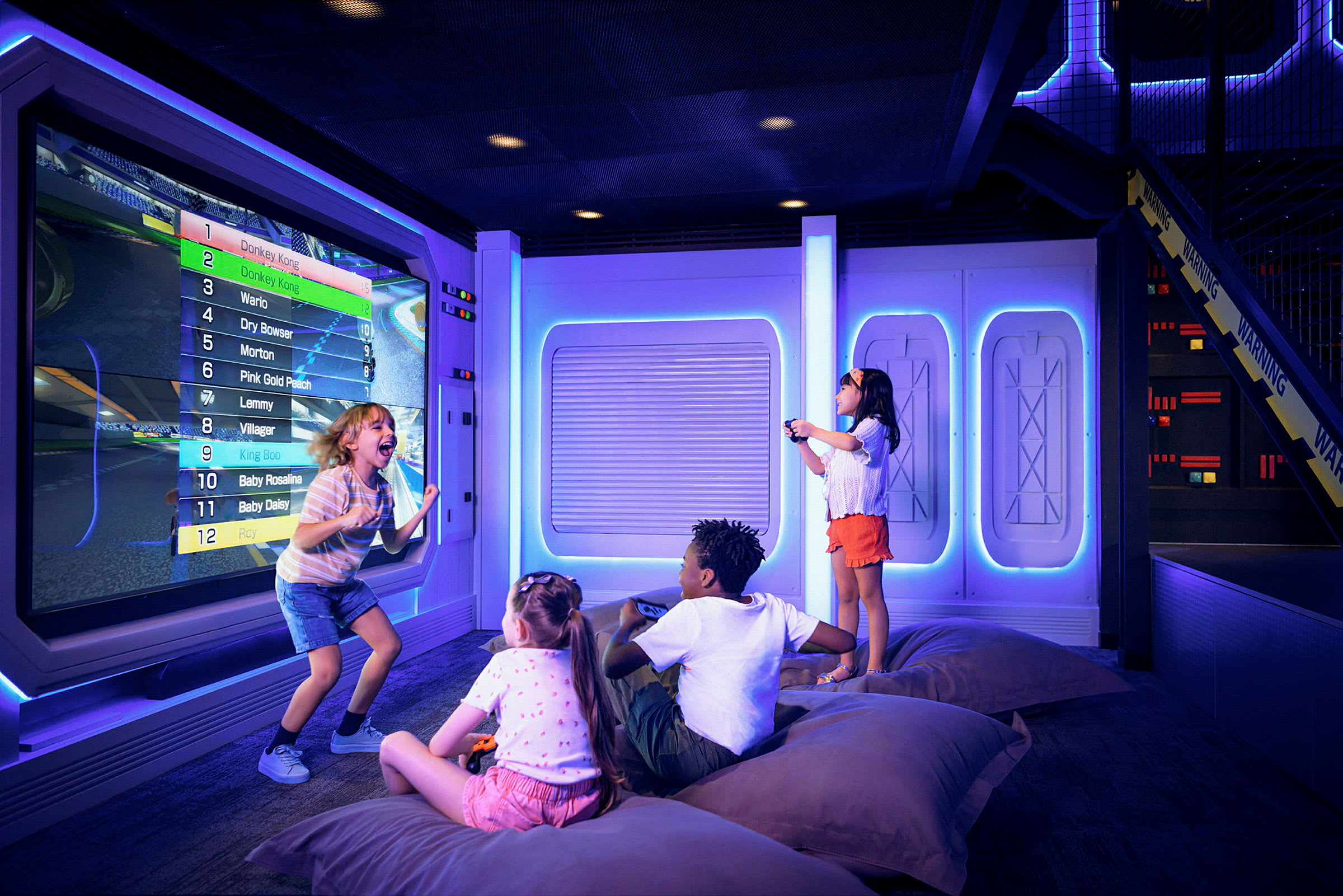 Barn spelar videospel på en stor skärm i ett futuristiskt rum. (AI-genererad text)