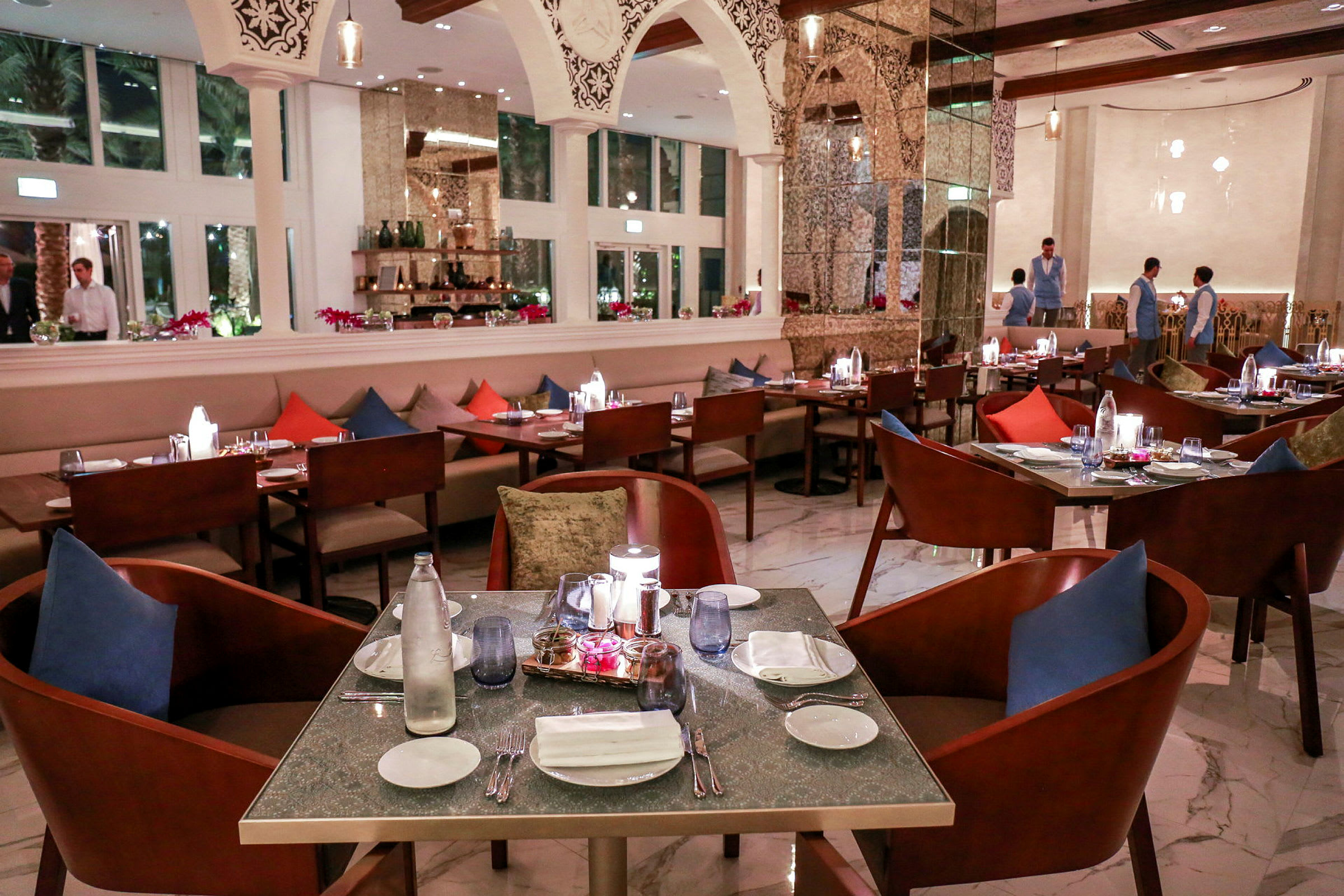 En elegant restaurang med dukat bord, färgade kuddar och moderna inredningsdetaljer. (AI-genererad text)