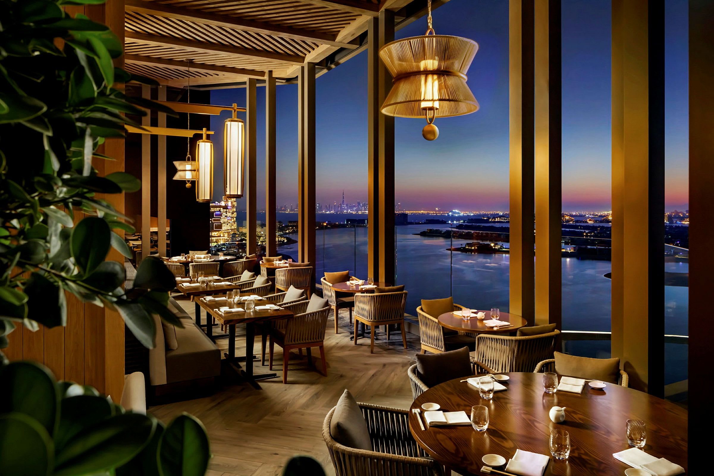 Utsiktsrestaurang med elegant inredning och kvällsutsikt över hav och stad. (AI-genererad text)