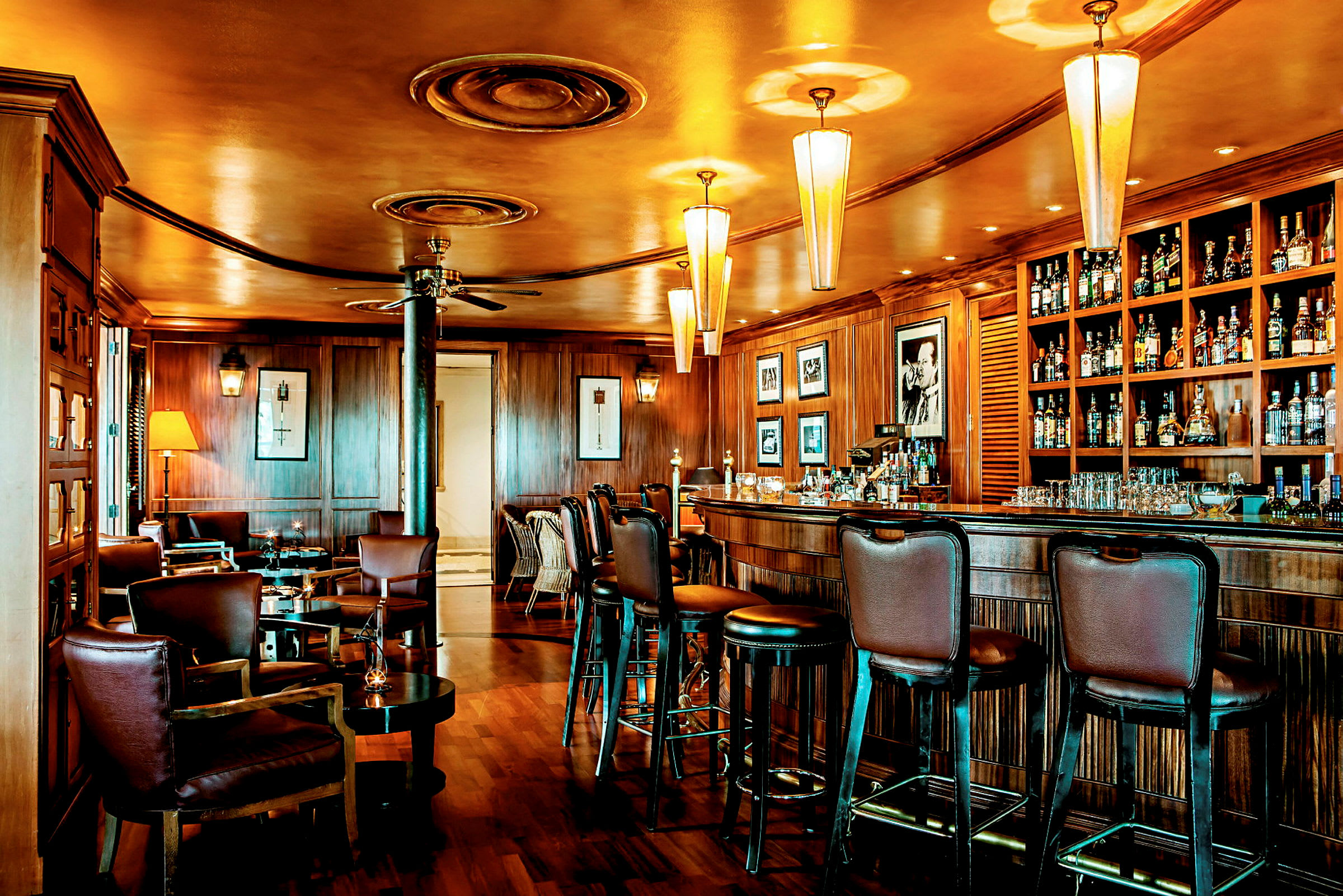 En elegant bar med träpanelen och bekväma stolar. Taklampor lyser upp rummet. (AI-genererad text)