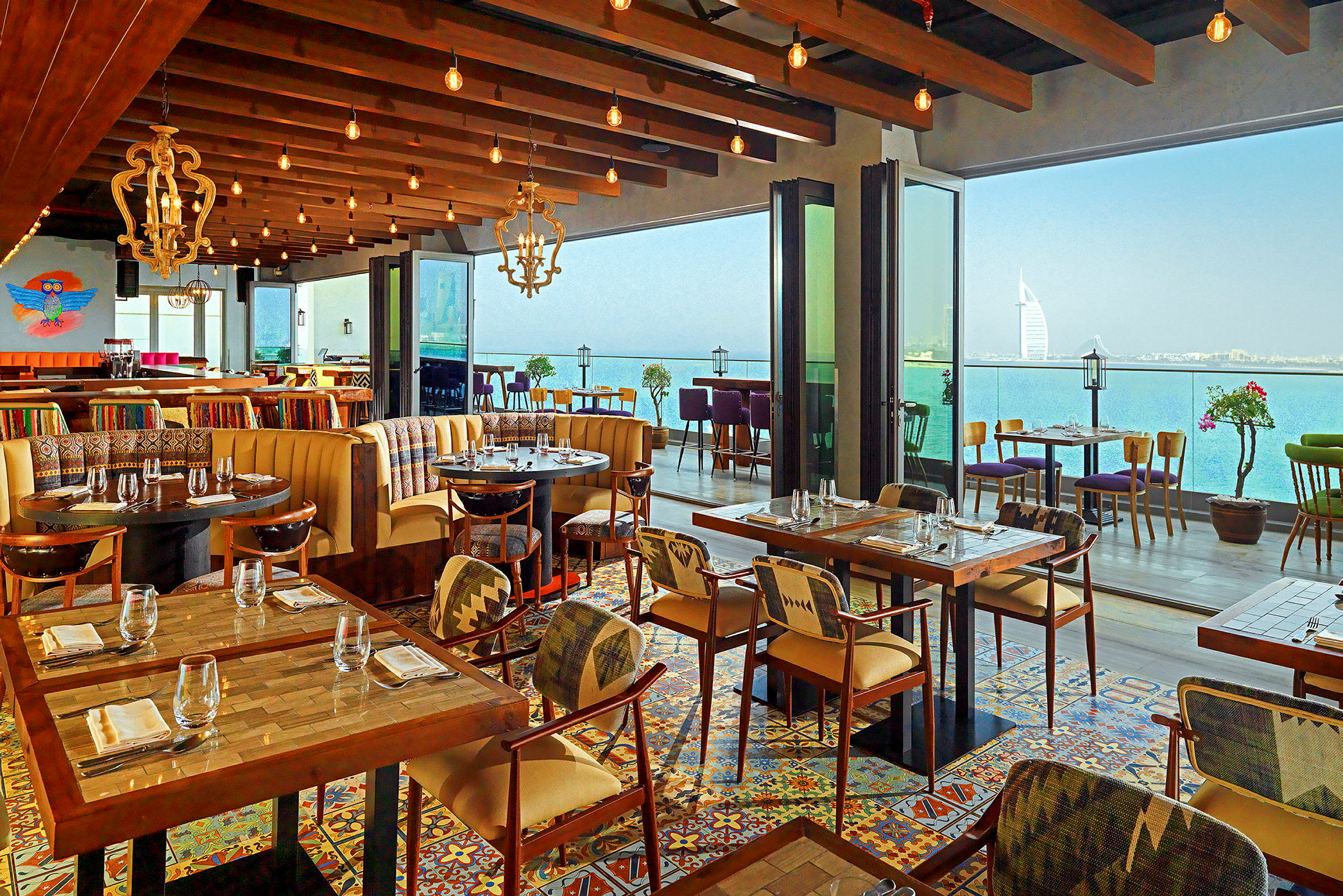 Restaurang med moderna möbler, färgat kakelgolv och panoramautsikt över havet. (AI-genererad text)