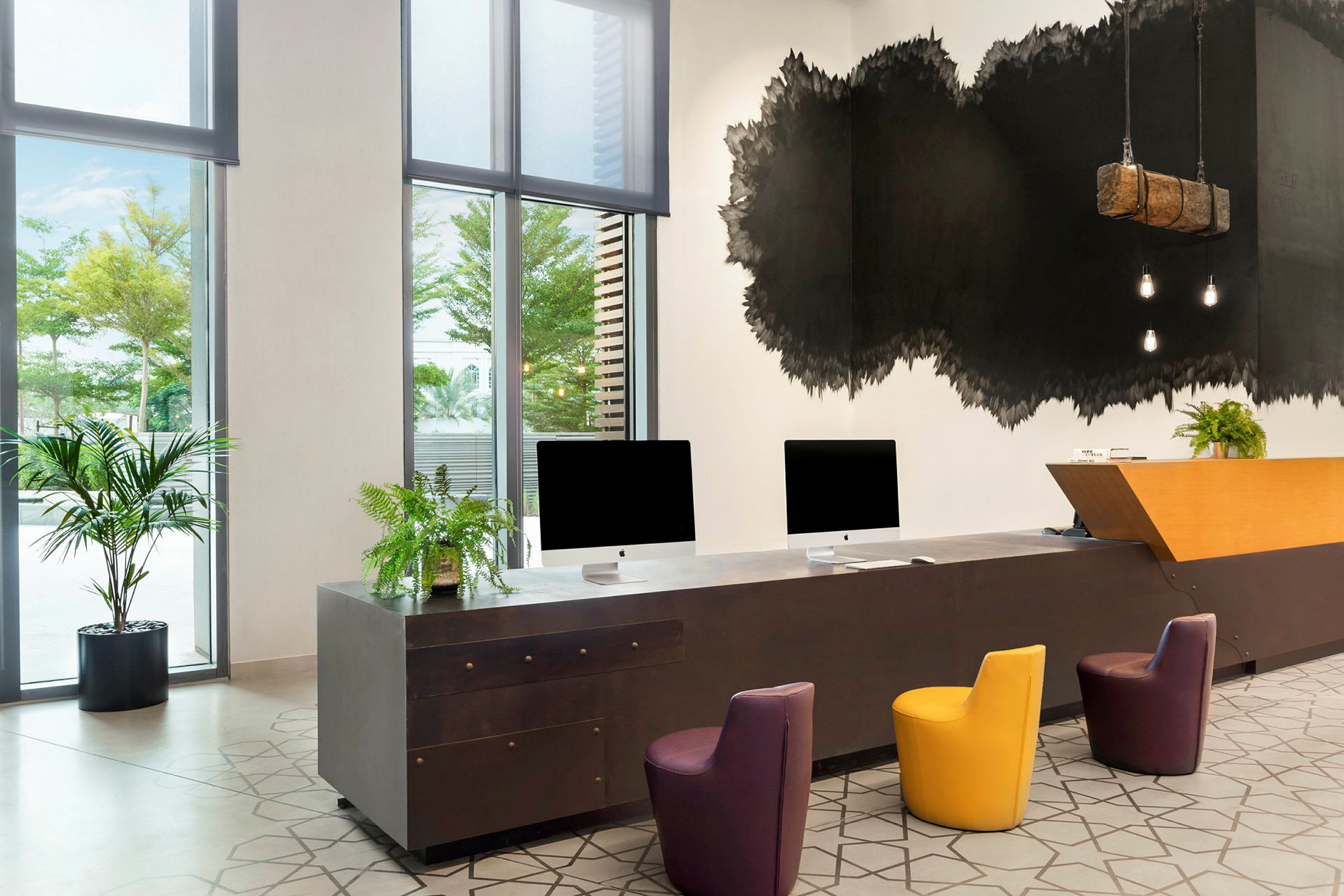 Modernt designad receptionsdisk med datorer och färgglada sittplatser. (AI-genererad text)