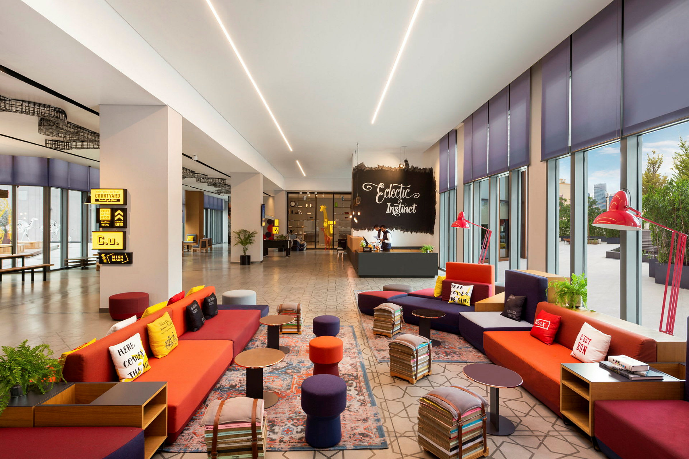 En modern och färgglad hotellobby med soffor och små bord. Stora fönster ger naturligt ljus. (AI-genererad text)