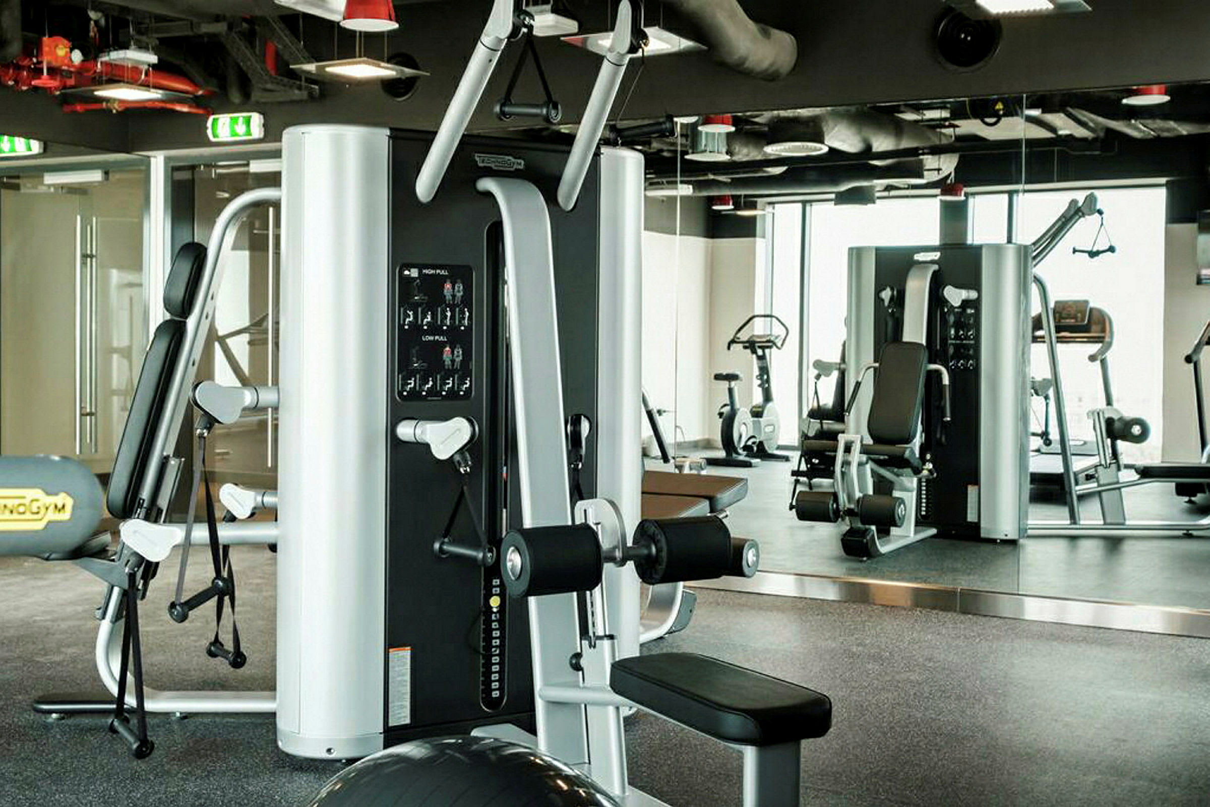 Ett gym med olika träningsmaskiner och spegelvägg. (AI-genererad text)