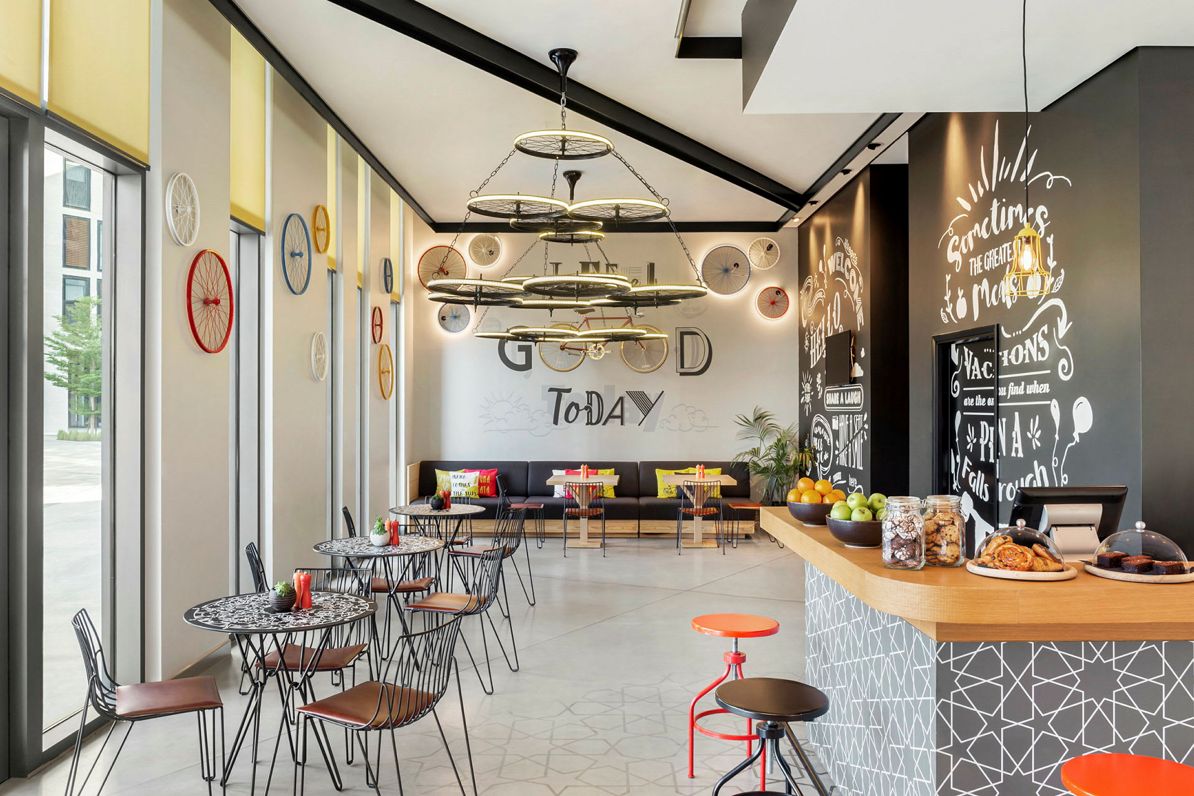 Ett modernt kafé med konstnärlig inredning, dekorerade väggar med cykelhjul och en central taklampa i industriell stil. (AI-genererad text)