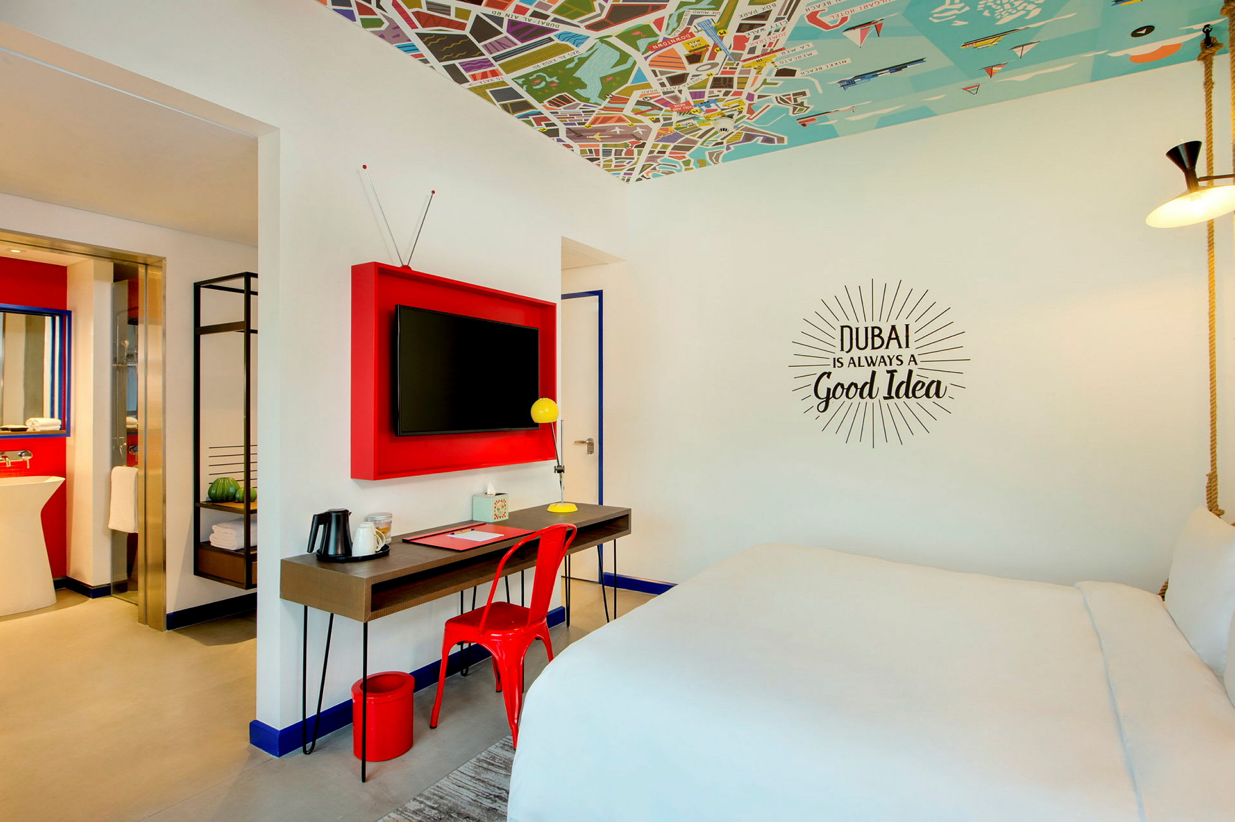 Modernt inrett hotellrum med stor säng, skrivbord med stol och TV på väggen. (AI-genererad text)