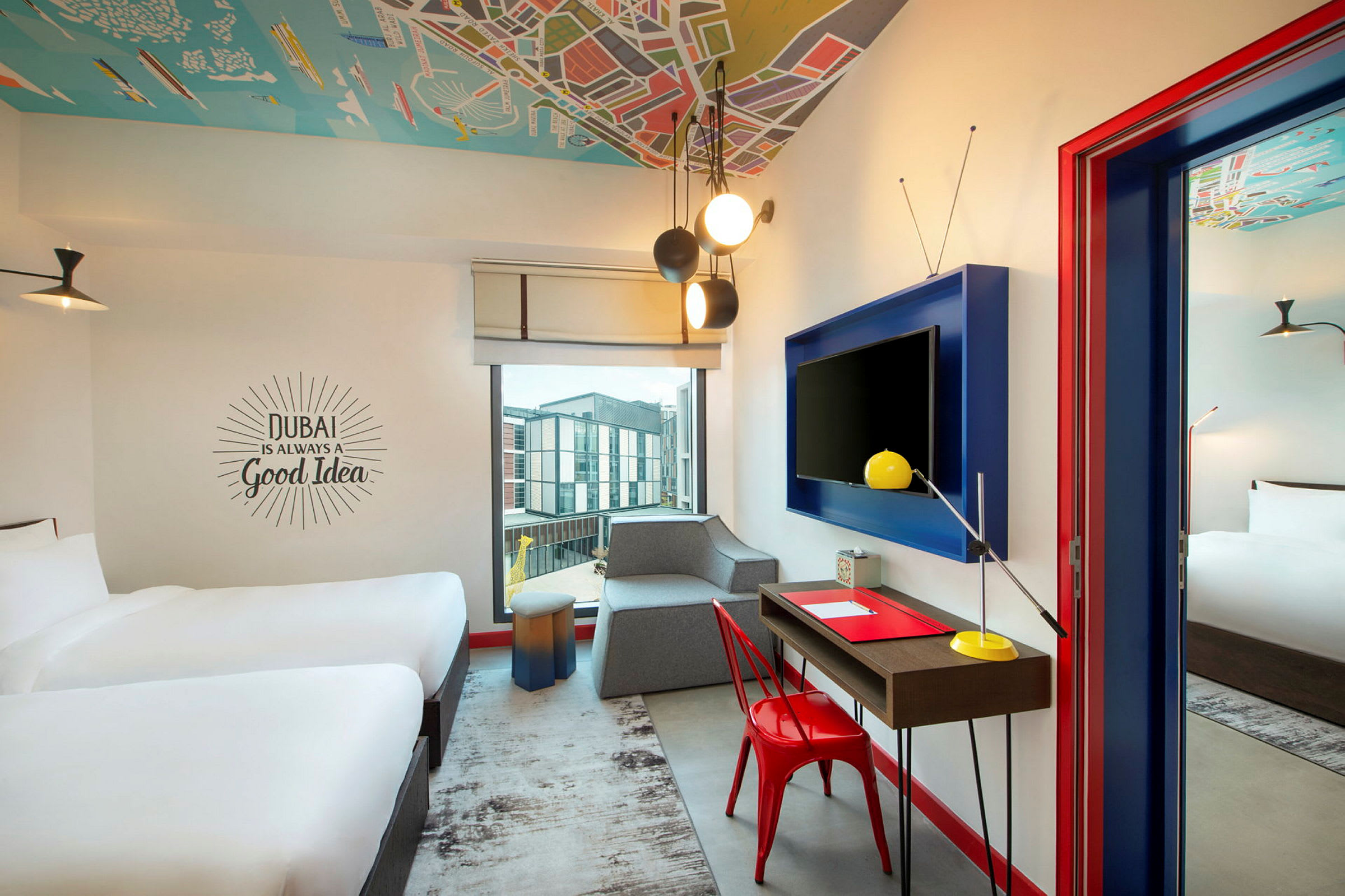 Ett hotellrum med två sängar, en skrivbordsstol och ett bord framför en TV på väggen samt ett stort fönster. (AI-genererad text)