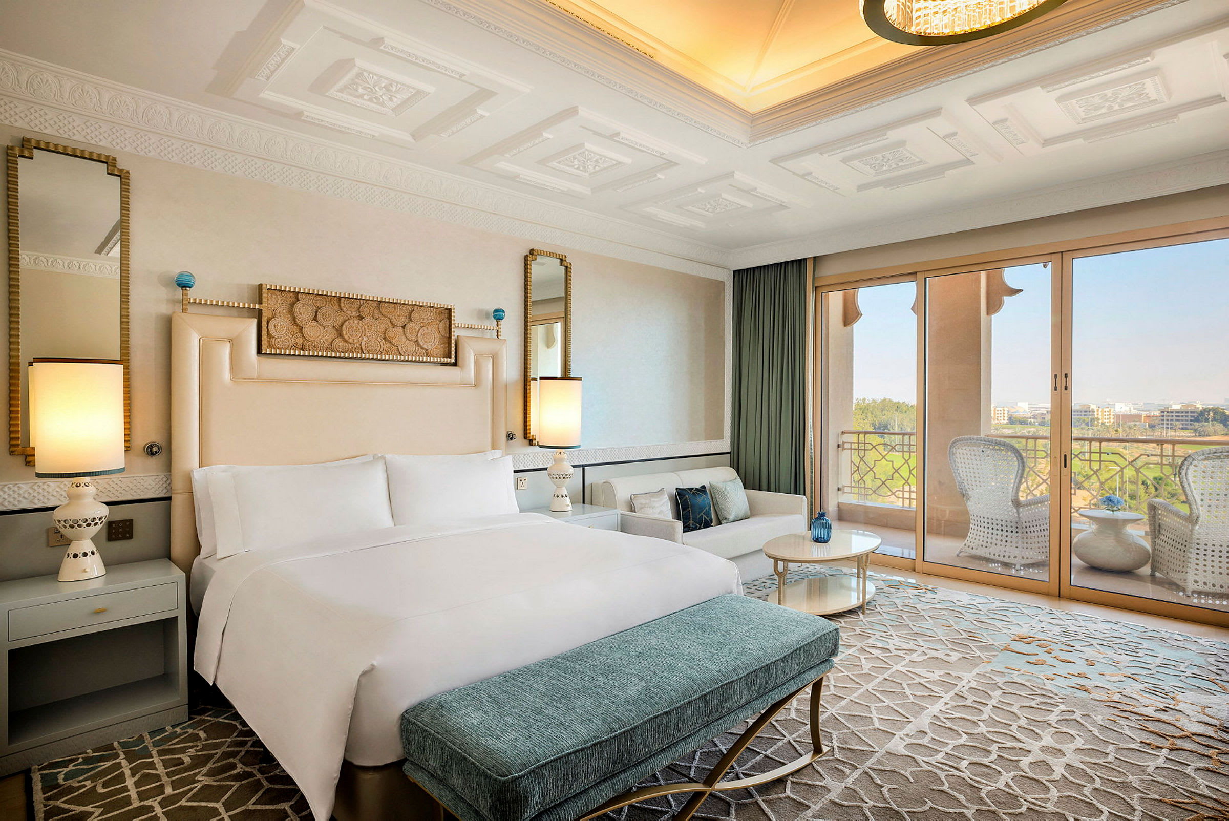 Ett elegant hotellrum med en stor dubbelsäng, sittgrupp, och en balkong som erbjuder utsikt över landskap. (AI-genererad text)