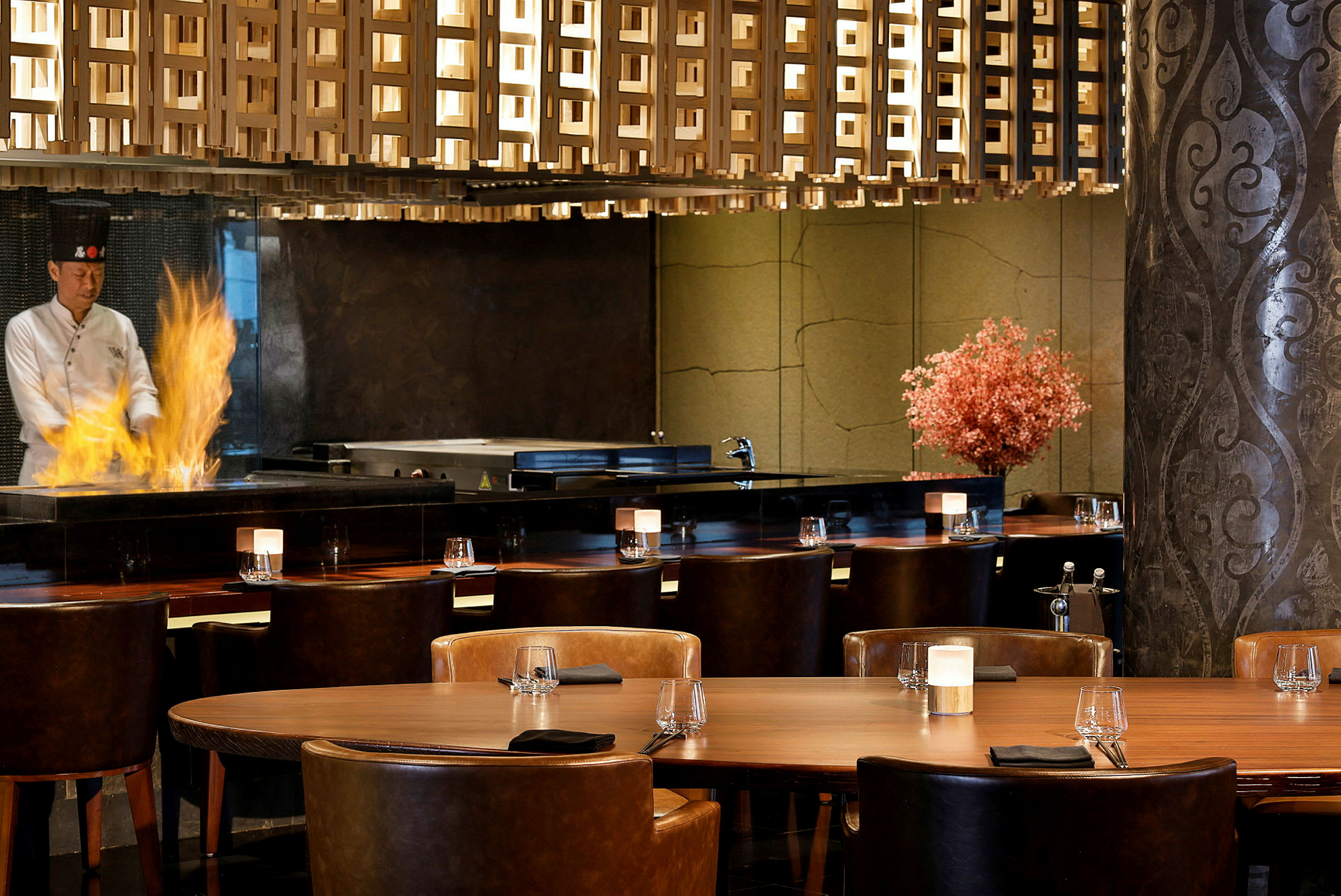 Inredning av en restaurang med bord, stolar och en eld på en matlagningsyta. (AI-genererad text)
