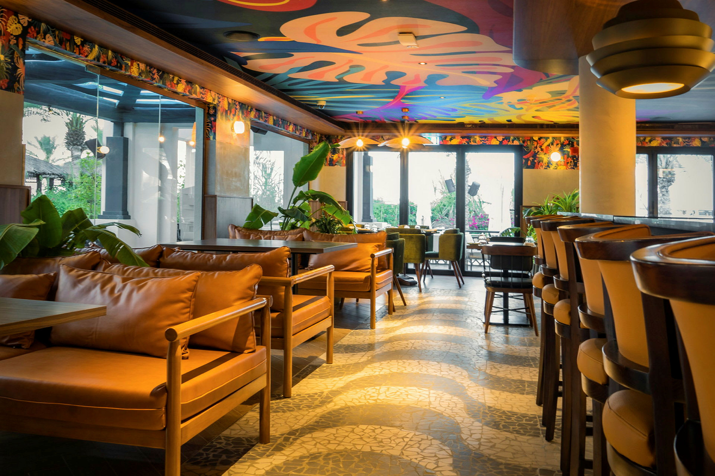 En ljus restaurang med färgstarkt dekorerat tak och moderna sittmöbler. (AI-genererad text)