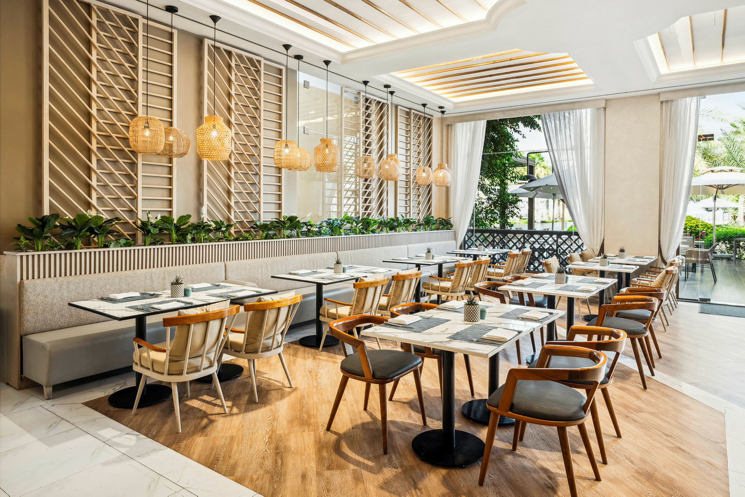 En modern, ljust inredd restaurang med trämöbler och stora fönster som släpper in naturligt ljus. (AI-genererad text)