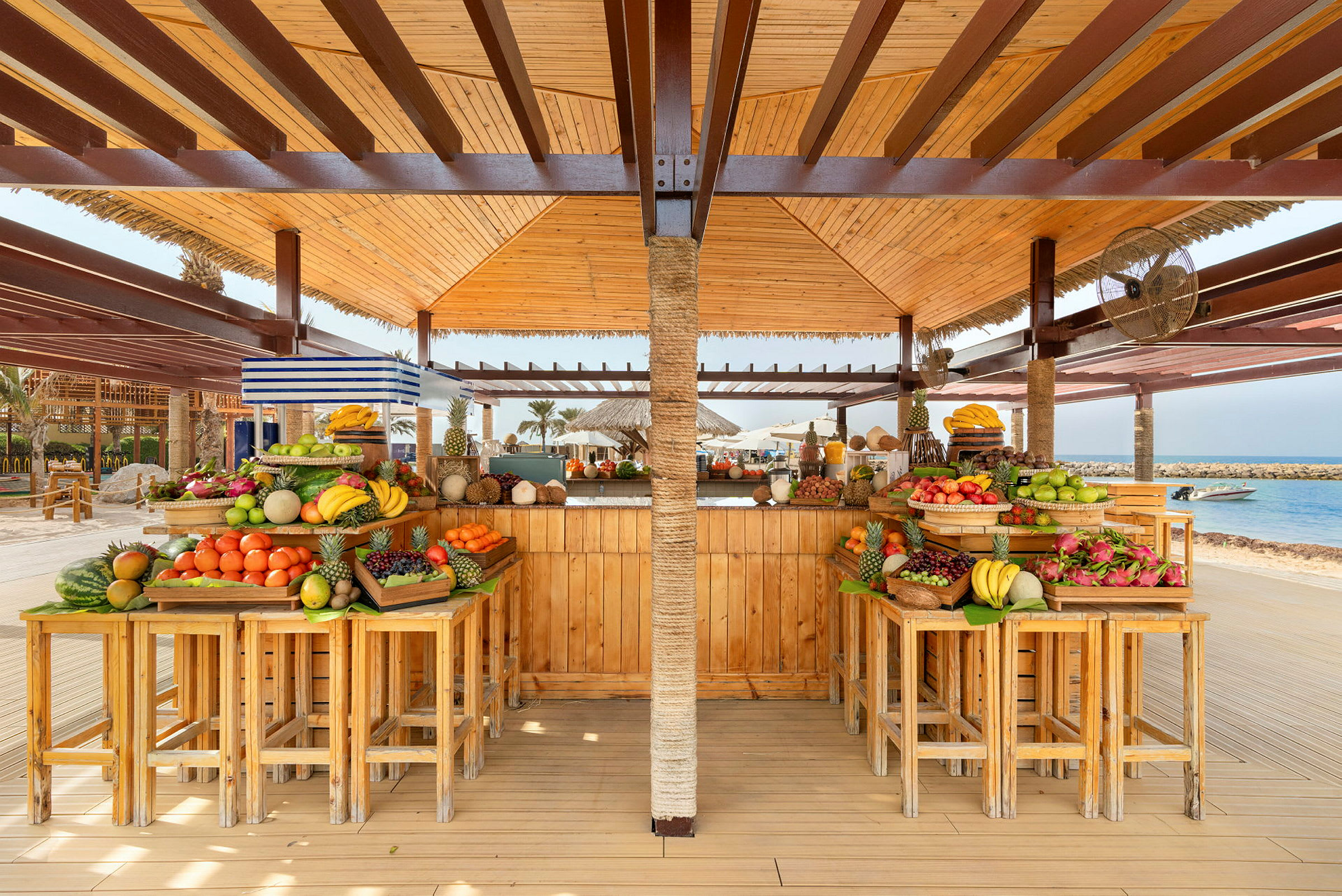 En strandbar med ett utbud av färska frukter på träbord. (AI-genererad text)