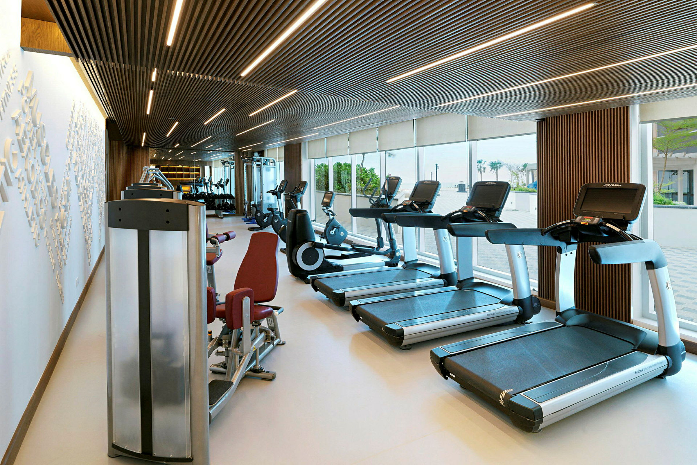 Ett modernt gym med träningsmaskiner som löpband och cyklar, med stora fönster som släpper in dagsljus. (AI-genererad text)