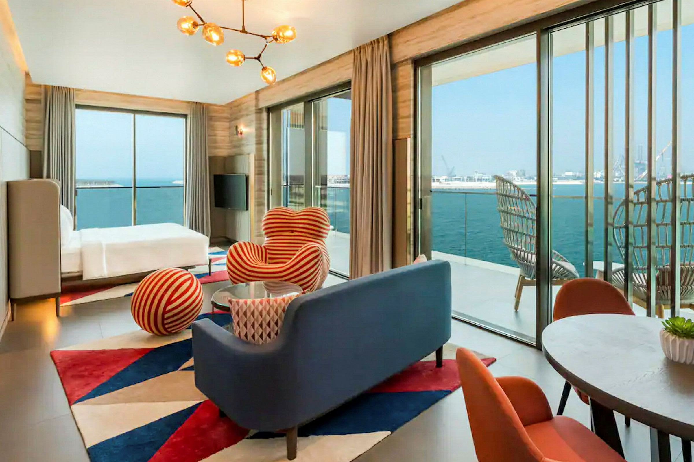 Ett modernt hotellrum med oceanutsikt, två fåtöljer, ett bord och glasväggar. (AI-genererad text)