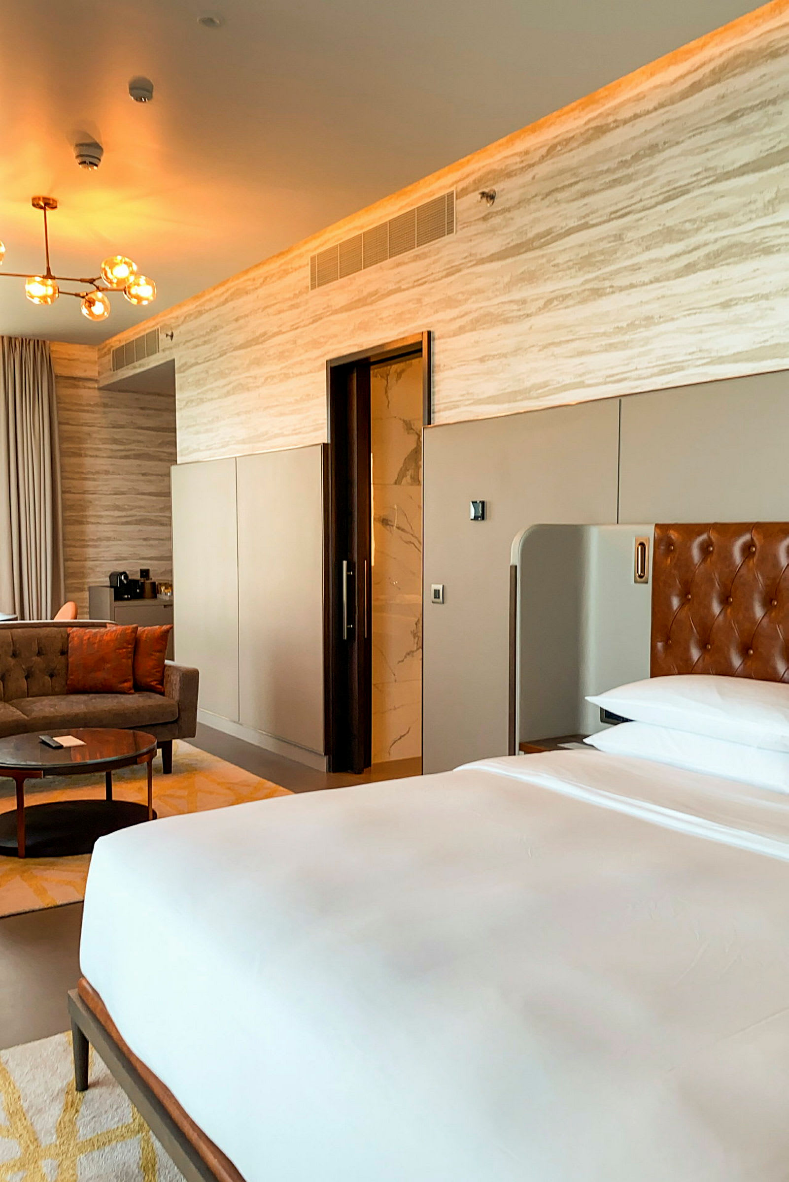 Ett modernt hotellrum med en säng, sittgrupp och ingång till badrum. (AI-genererad text)